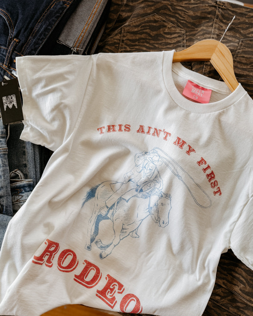 White t-shirt with red text and graphic of a bull on a hanger.