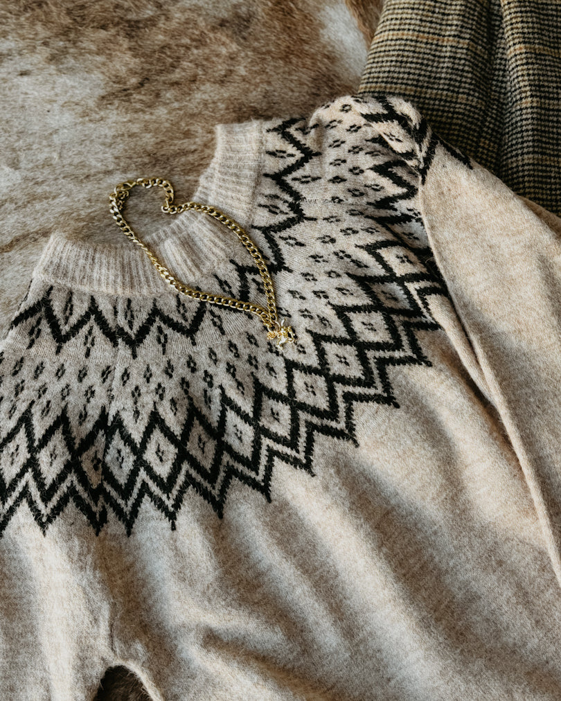 Beige sweater with black pattern on a textured surface