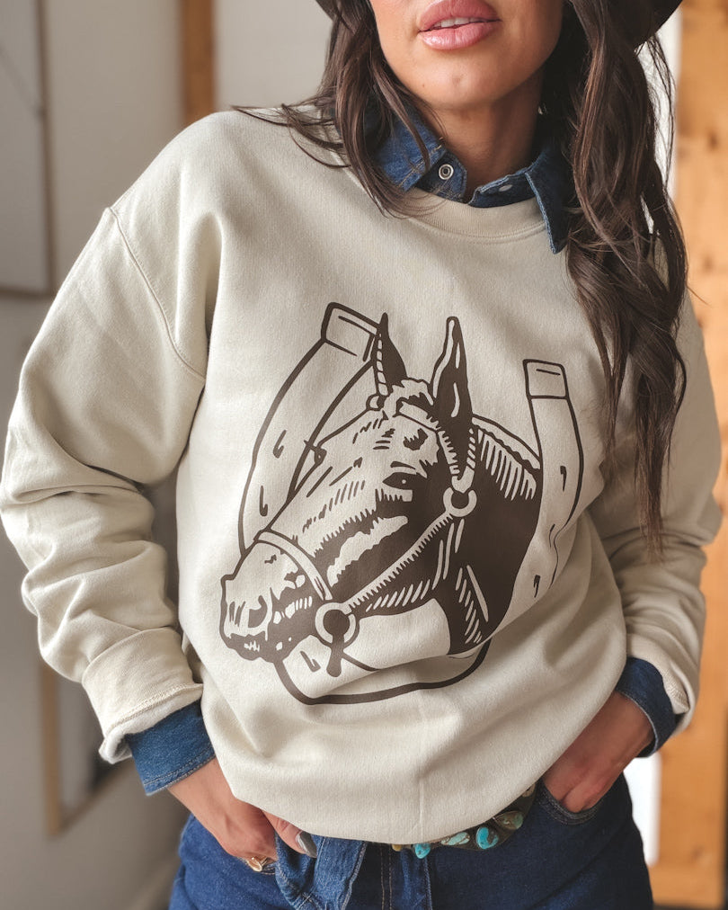 Woman in western hat and denim shirt wearing cream horse graphic sweatshirt, boho western style