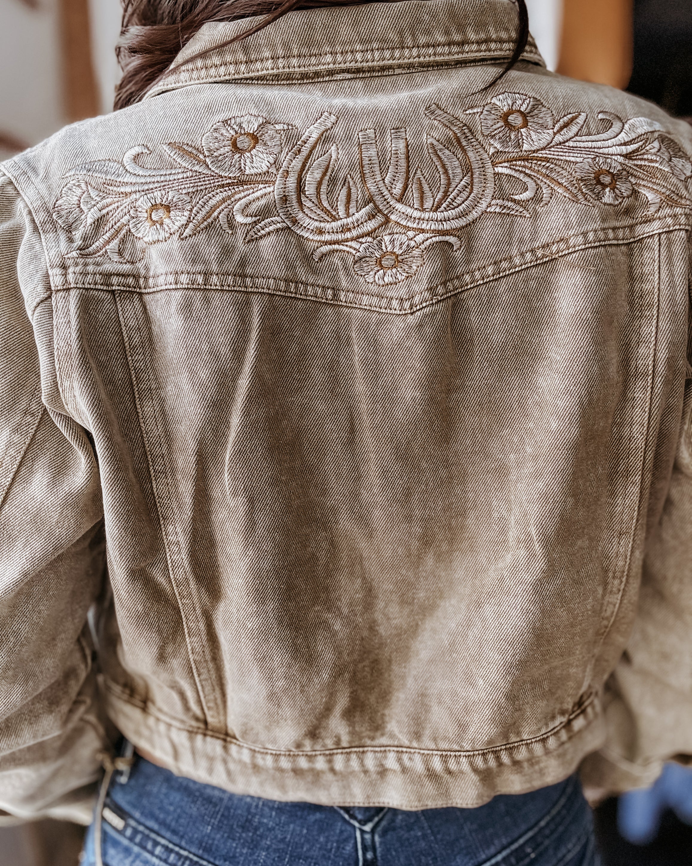 Western denim jacket with floral embroidery and horseshoe details, styled with blue jeans.