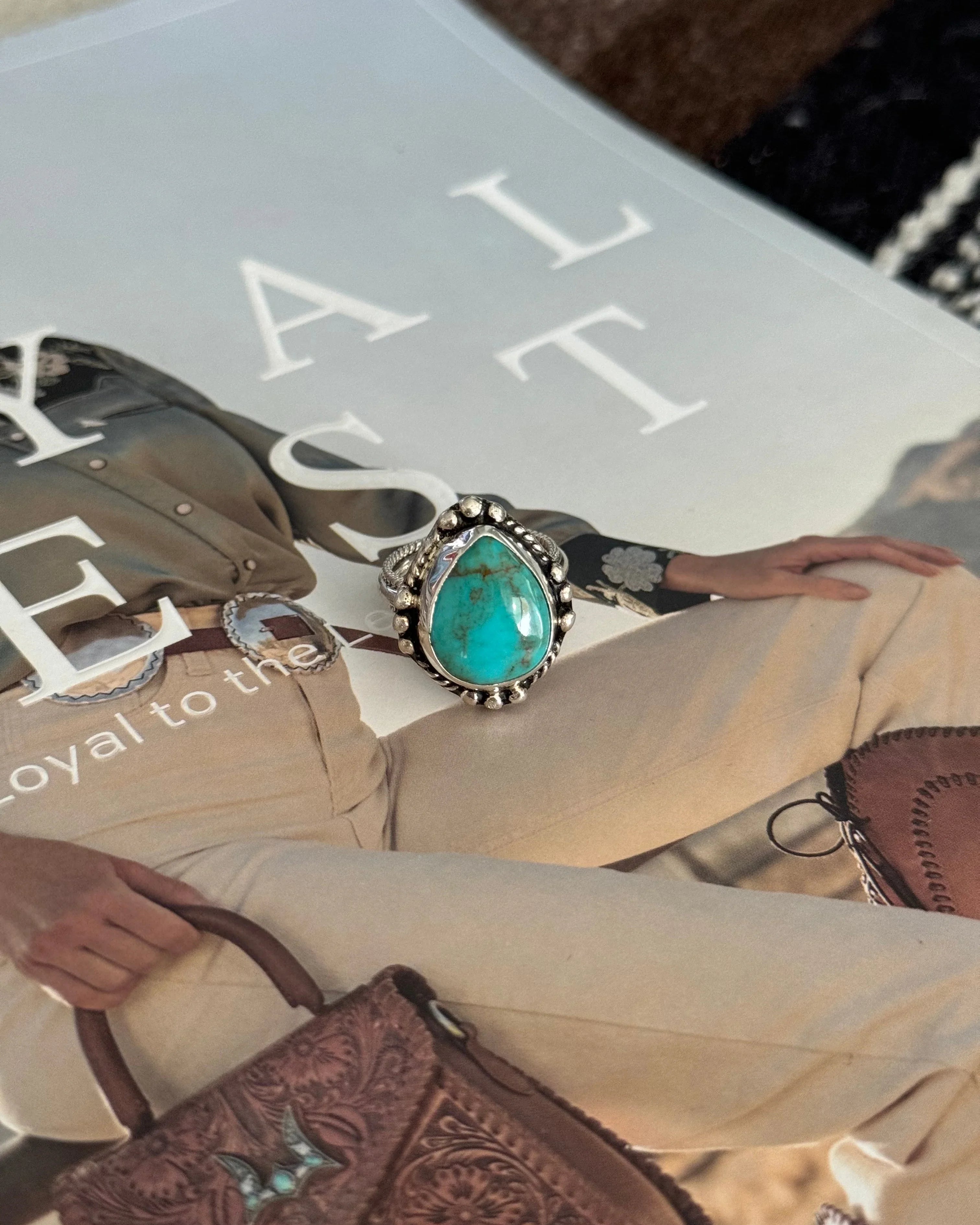 Turquoise western boho ring with silver detailing on magazine featuring western outfit