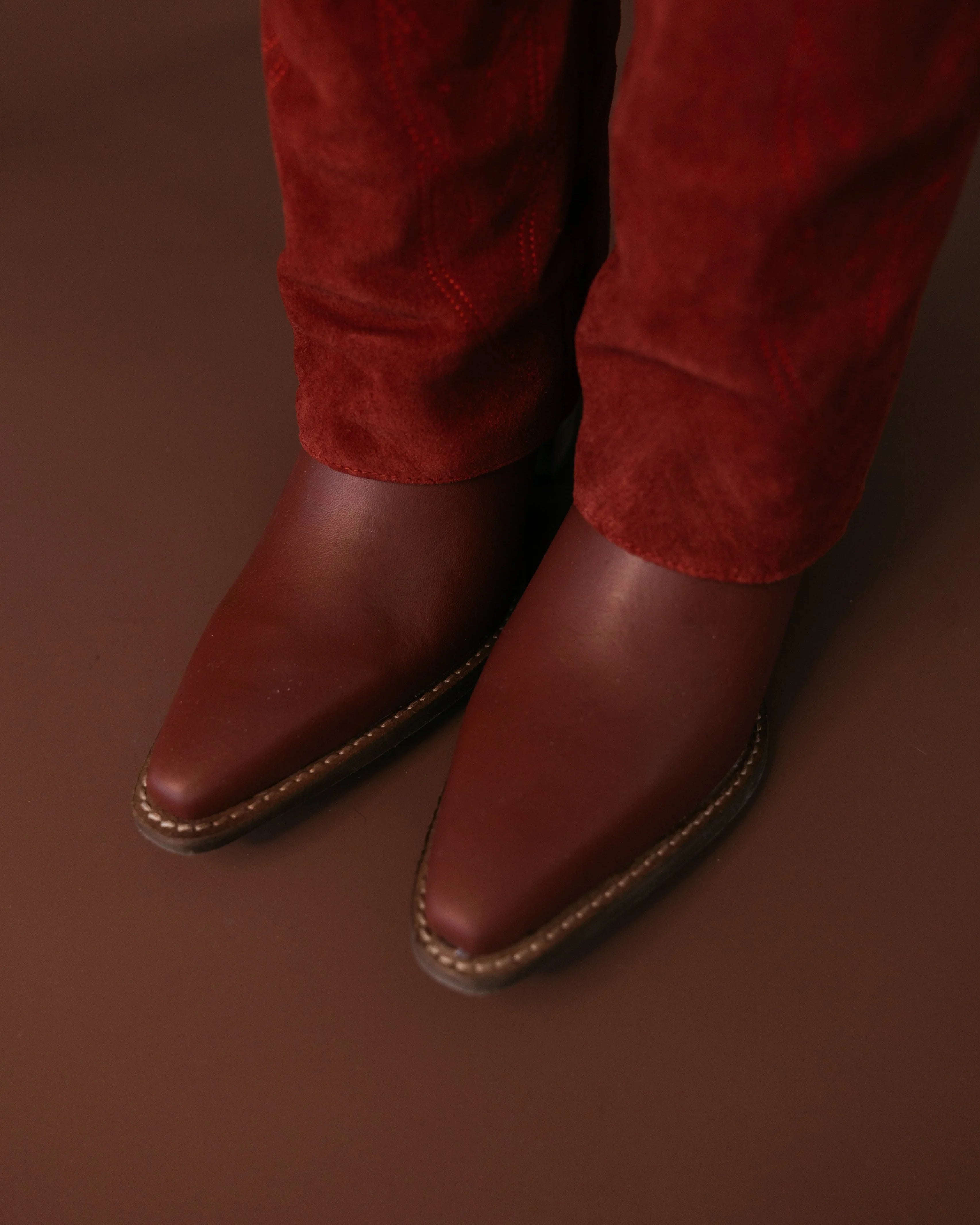Brown pointed-toe western boots with red suede pants, cowgirl boho style