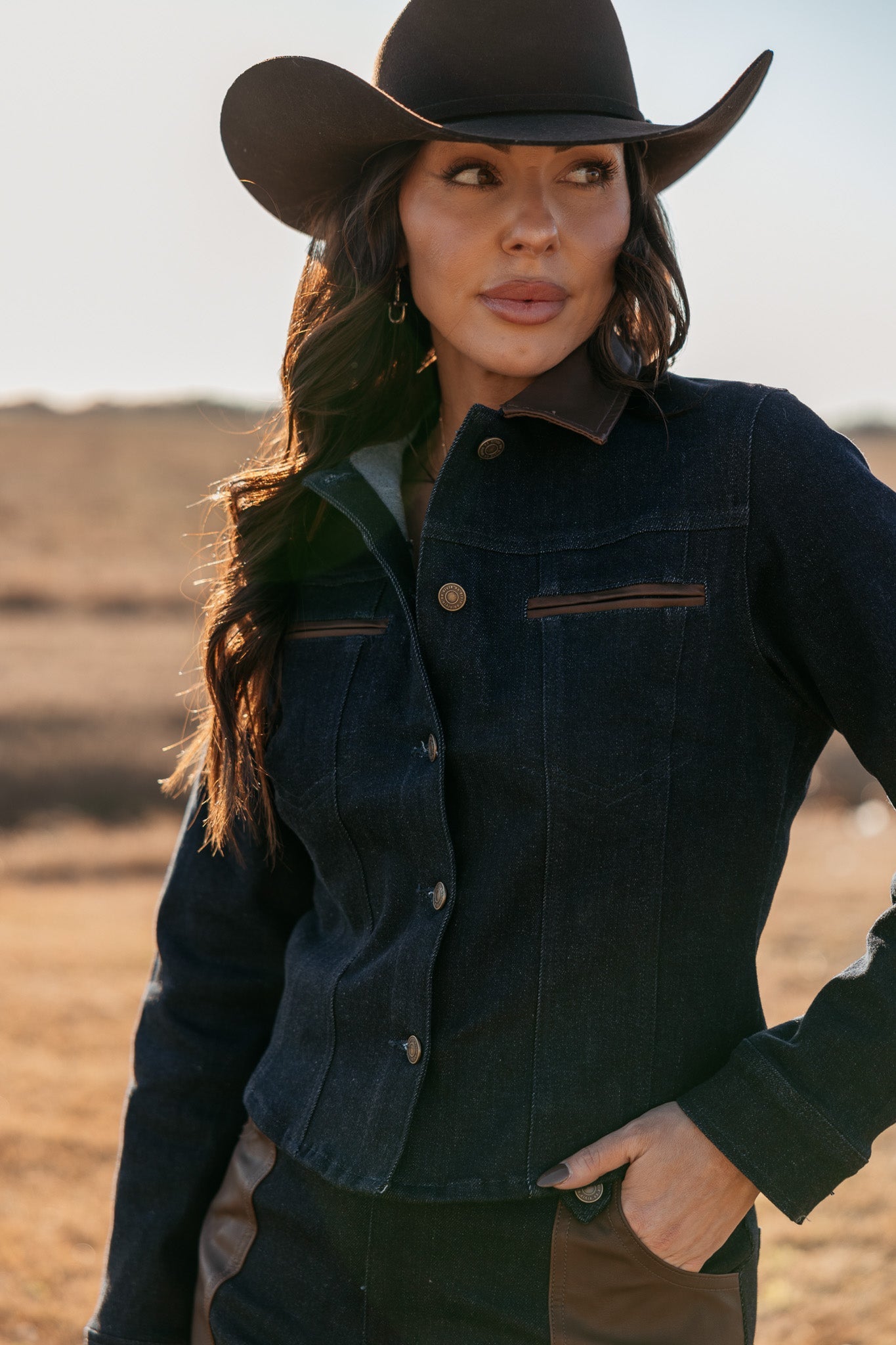 Woman in dark denim western jacket and cowboy hat outdoors, western boho fashion style