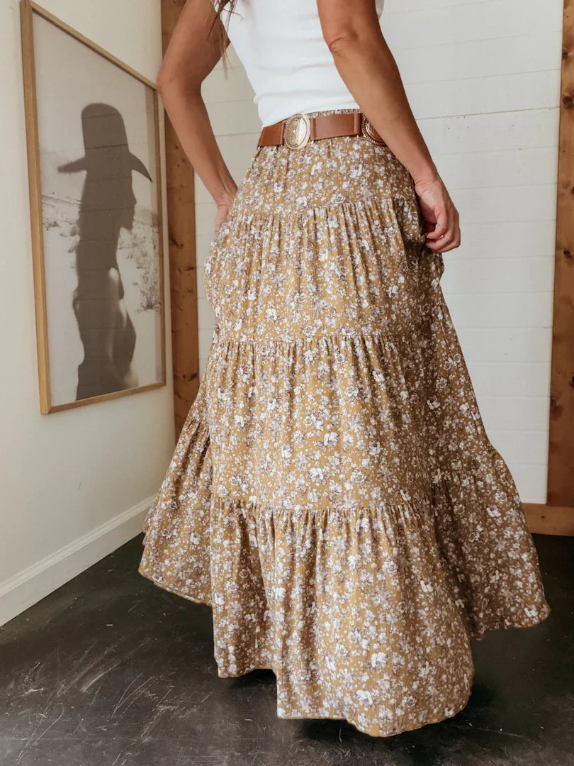 Person wearing a floral skirt in a room with a framed picture on the wall.