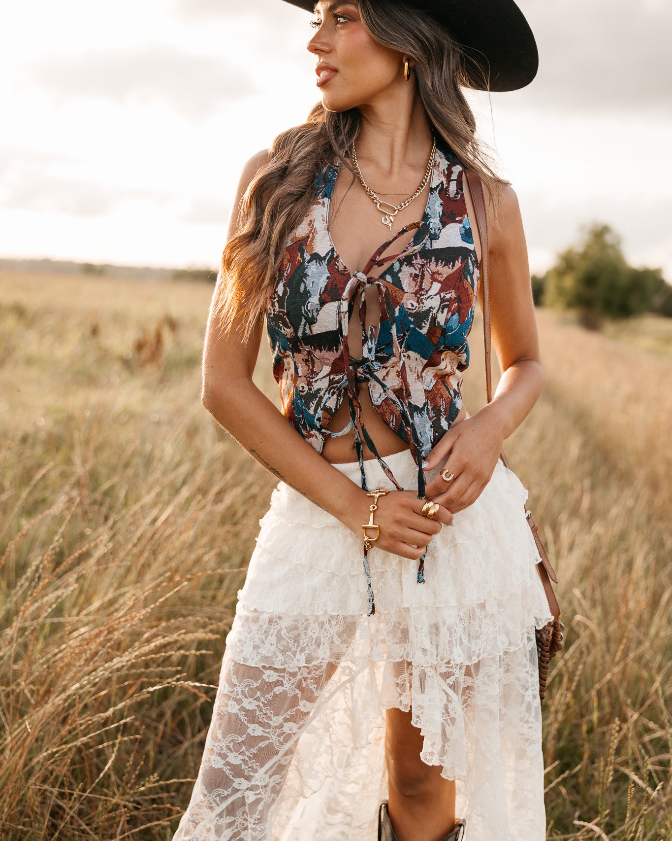 women wearing tie front halter top with horse pattern and a white skirt standing in a field.
