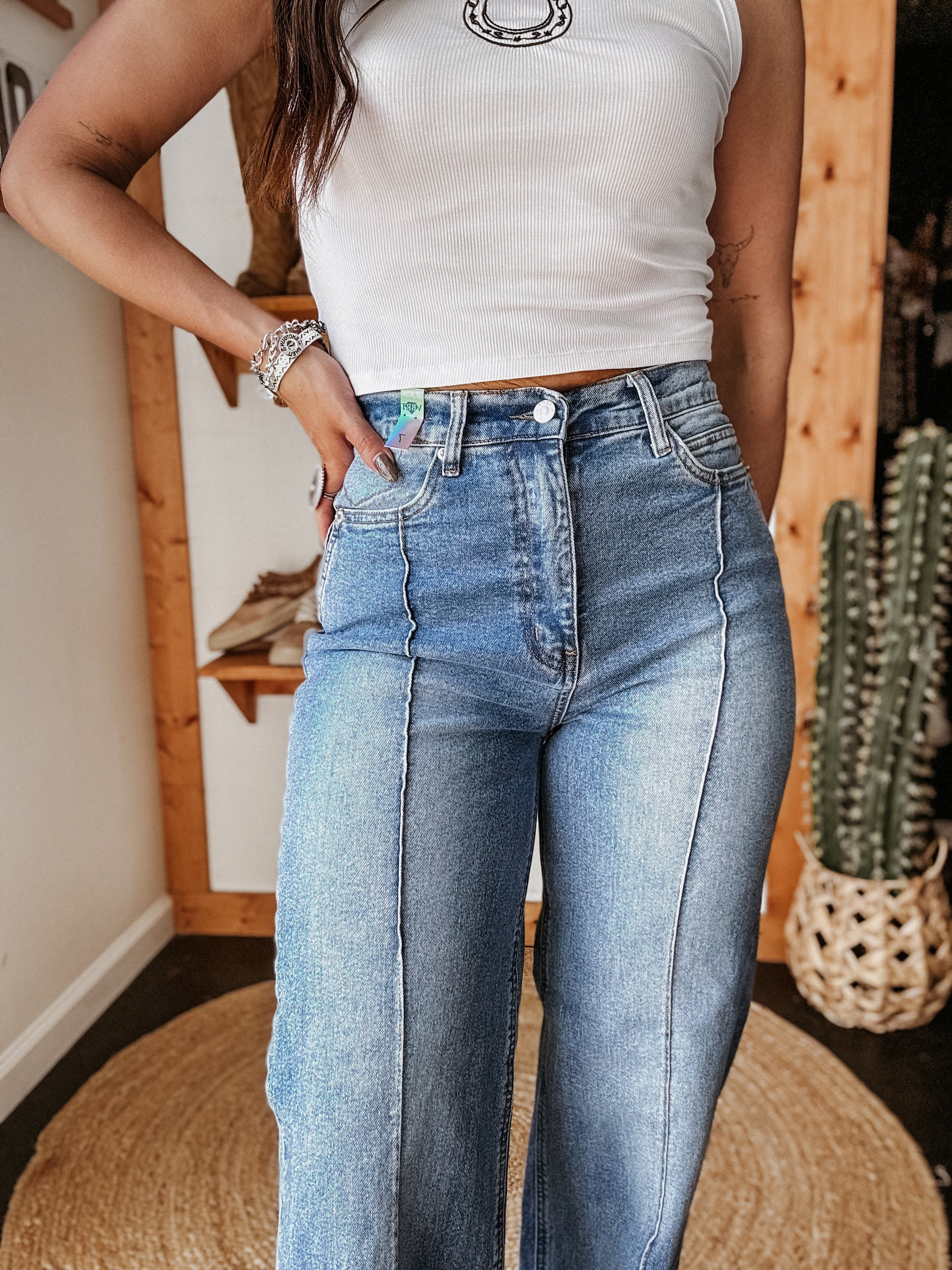 Woman wearing high-waisted wide leg jeans and white crop top with western accessories