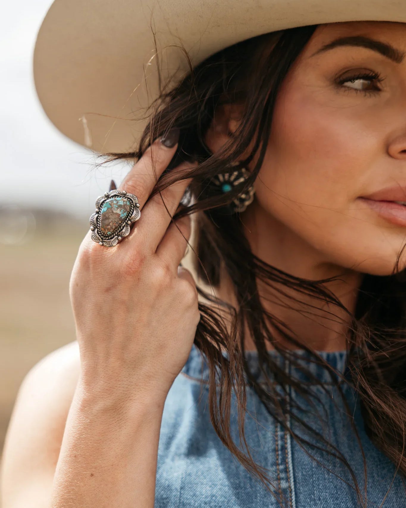 Woman in a cowboy hat wearing boho turquoise ring and denim top, western jewelry style