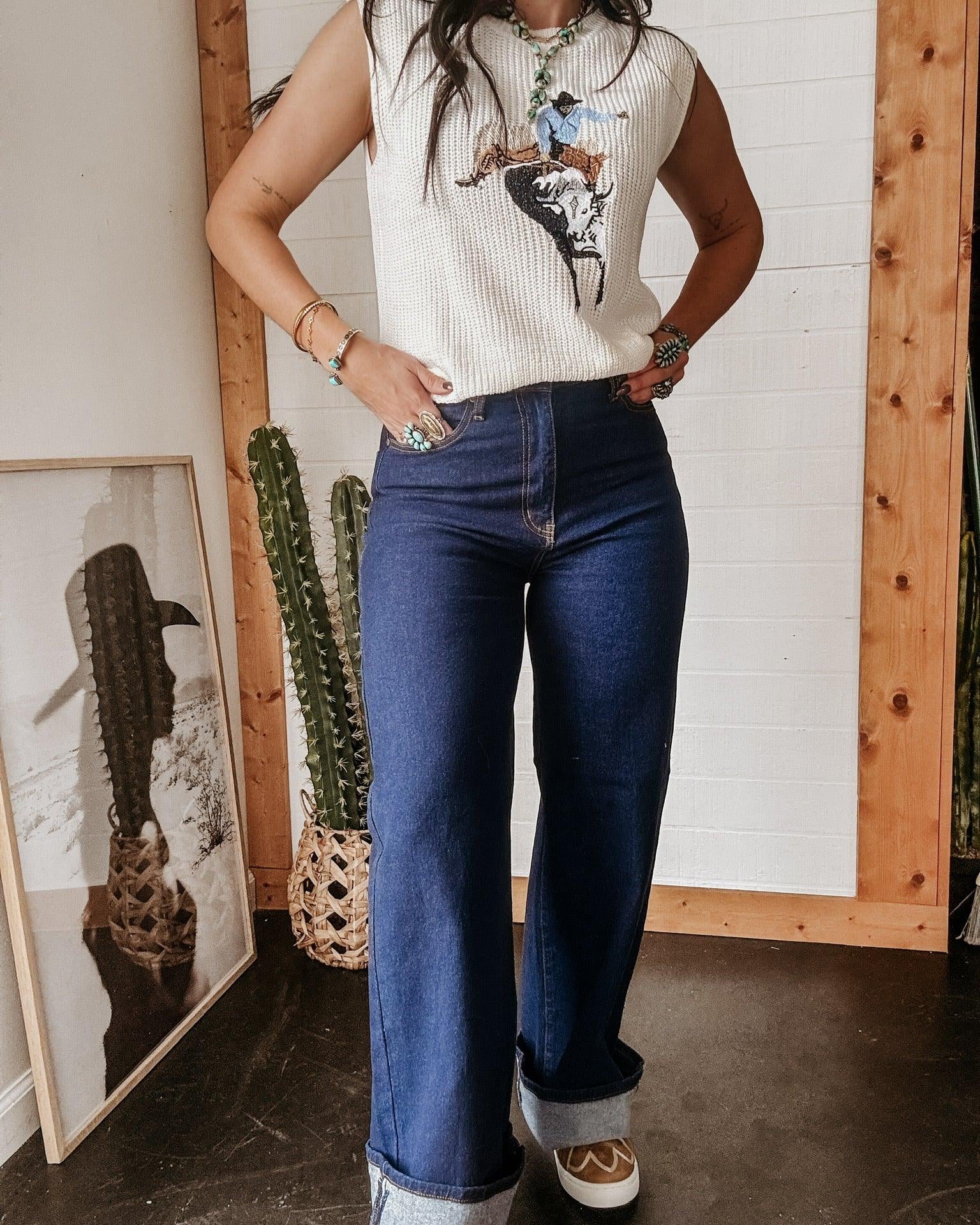 Woman in western graphic sleeveless top and high-waisted flared jeans with turquoise jewelry