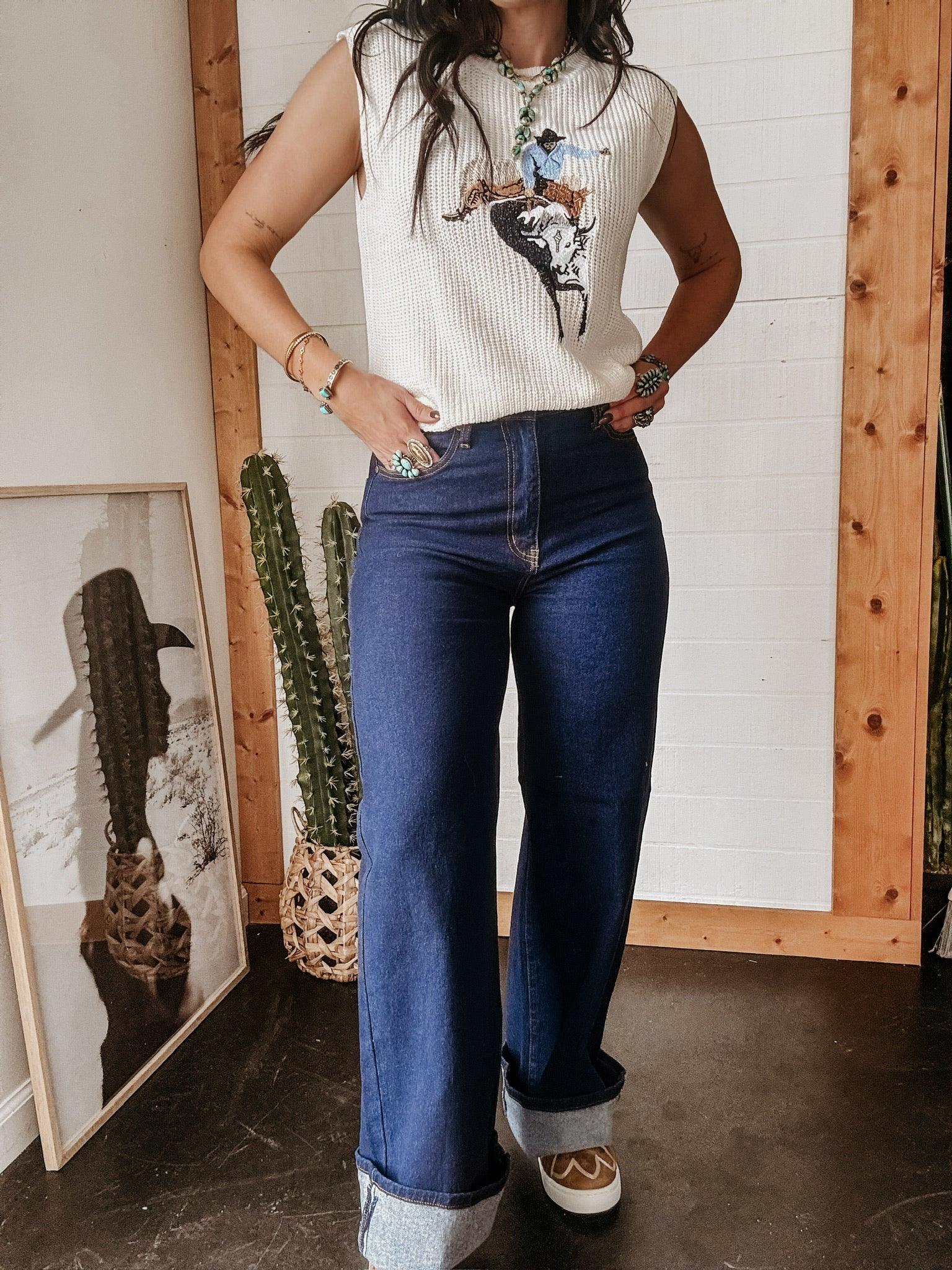 Woman in western graphic sleeveless top and high-waisted flared jeans with turquoise jewelry