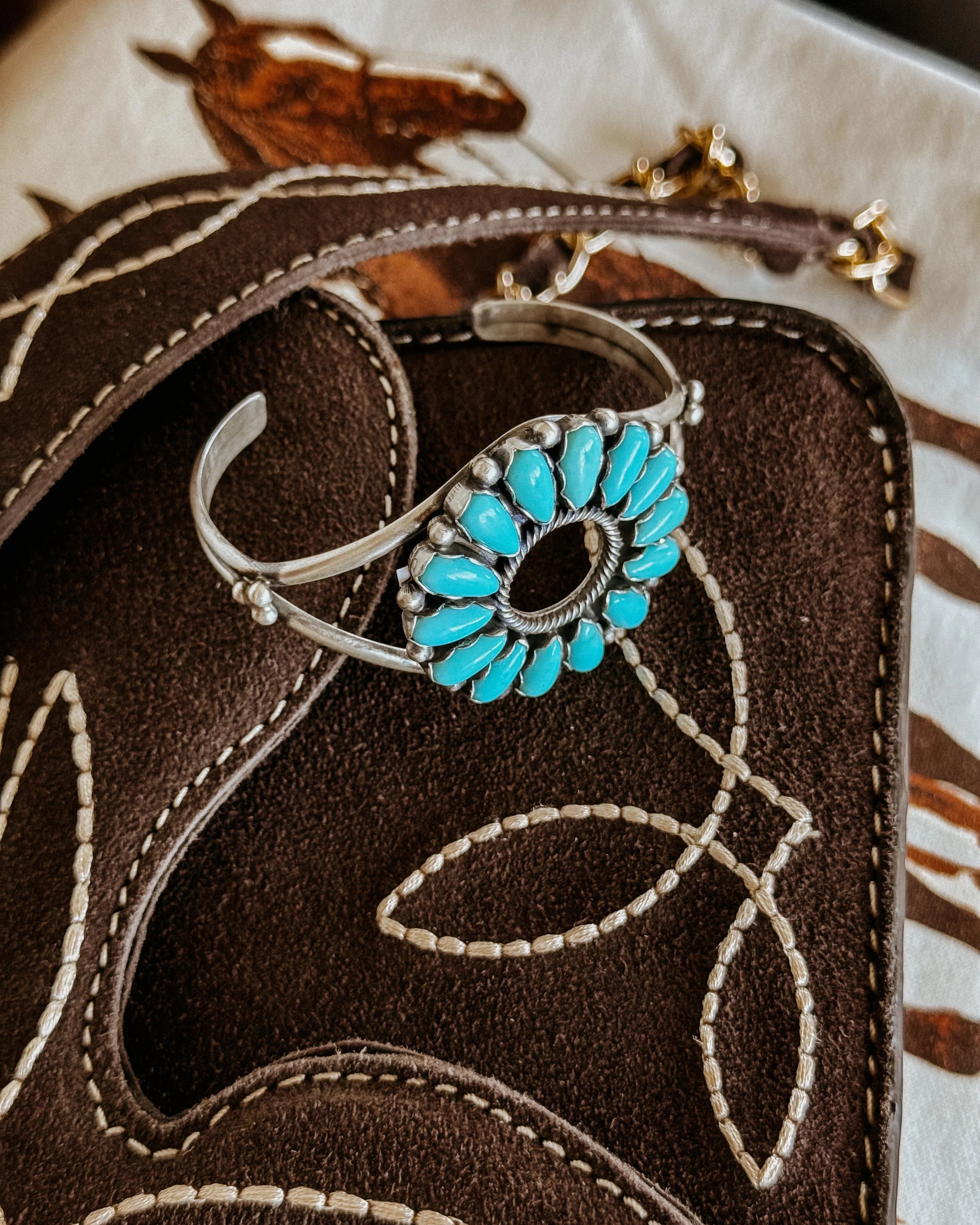 Turquoise western cuff bracelet on brown embroidered suede with horse print background