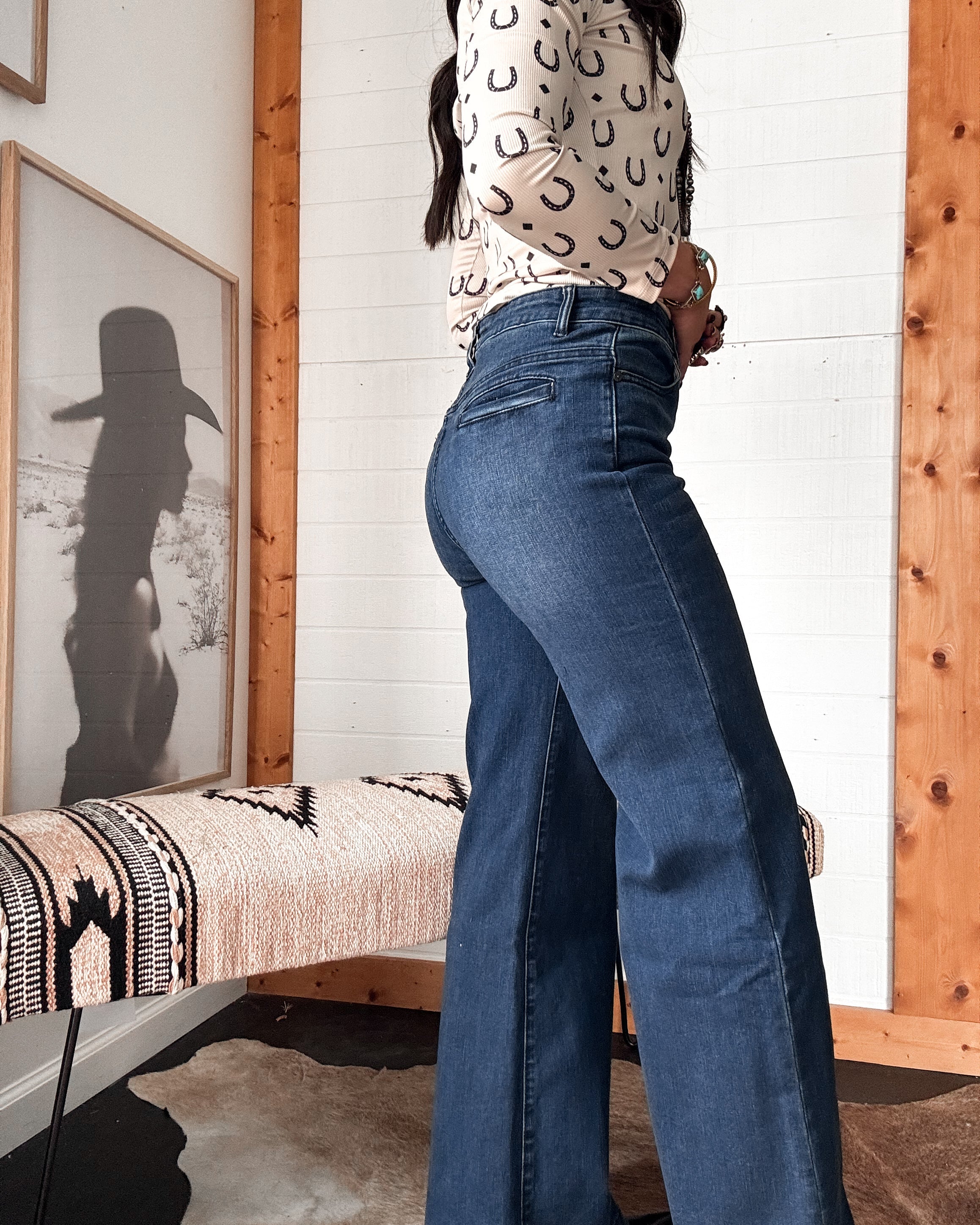 Woman in high waisted flare jeans and horseshoe print top, western-boho decor, side view