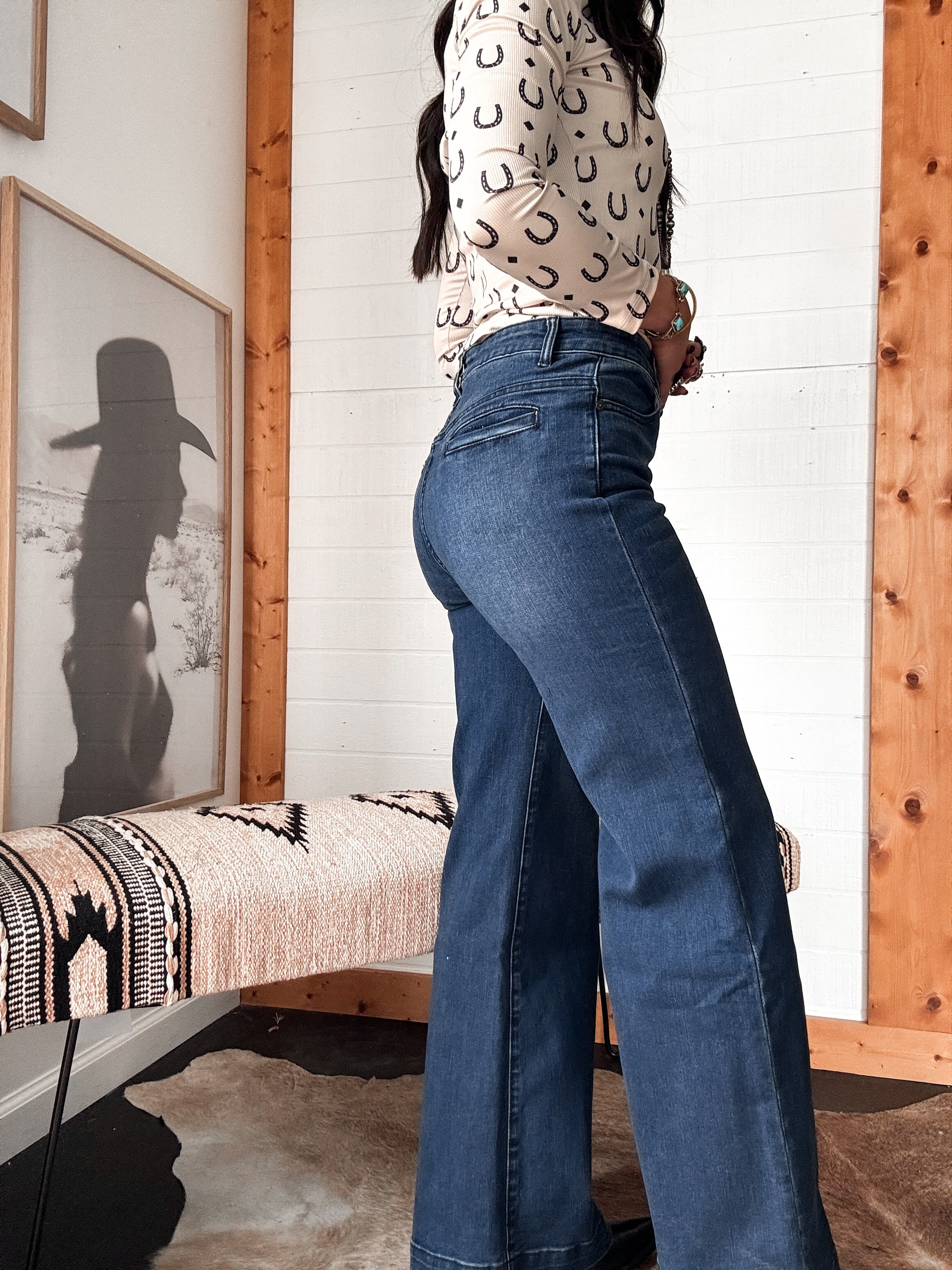 Woman in high waisted flare jeans and horseshoe print top, western-boho decor, side view
