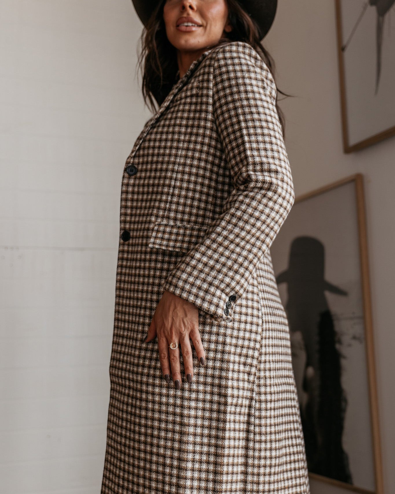 Woman in brown checkered long western coat and black cowboy hat, boho western fashion