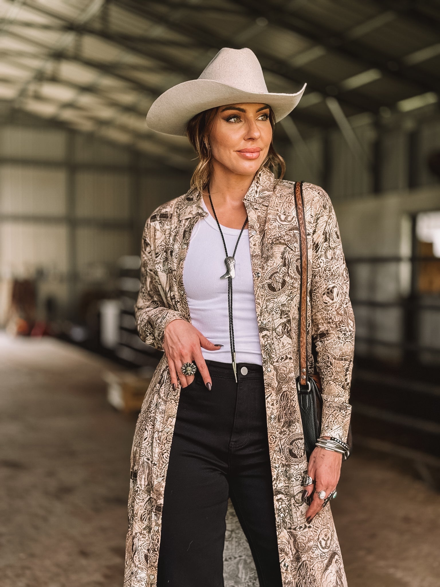 Woman in western boho outfit with cowboy hat, paisley duster, bolo tie and statement jewelry