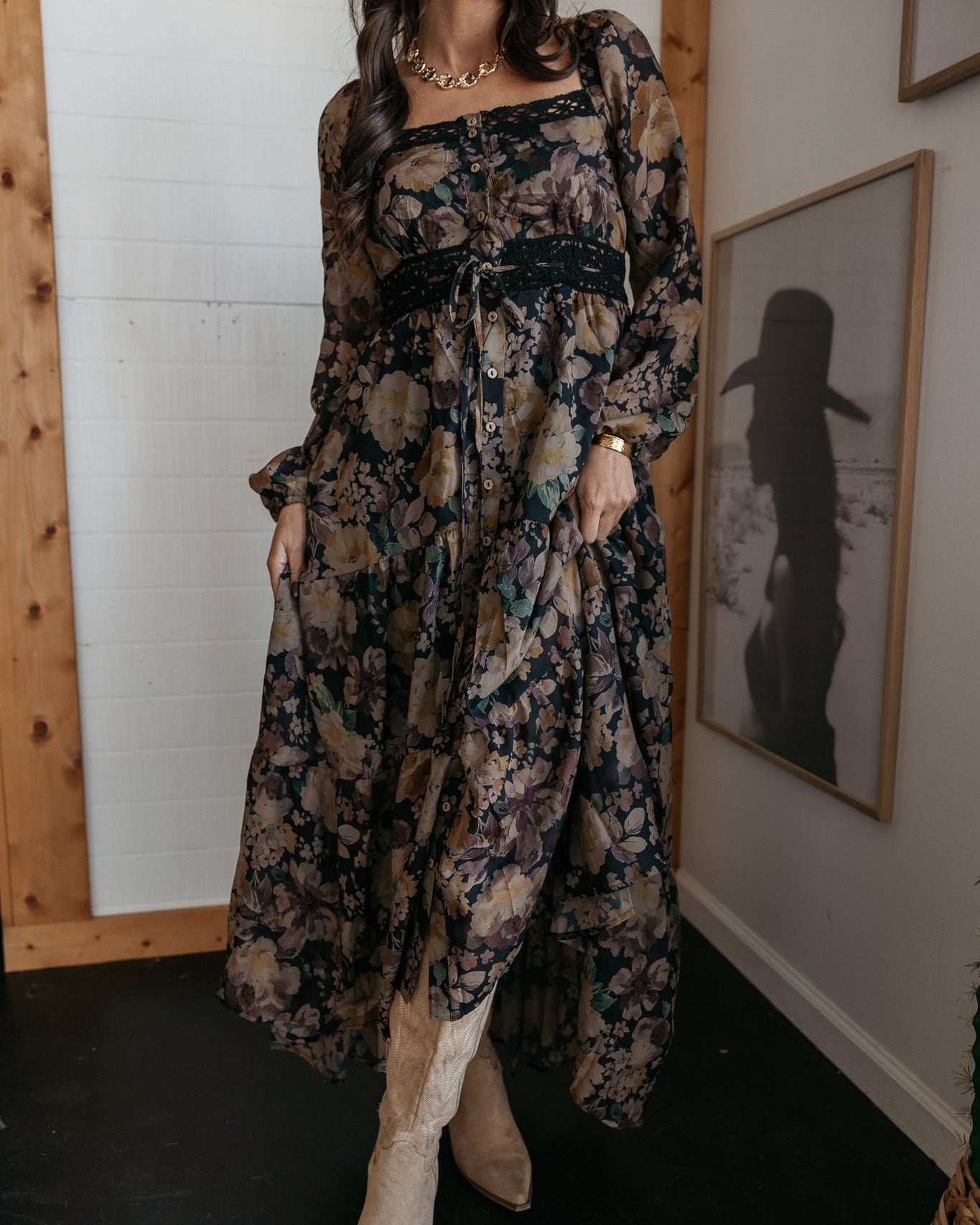 Woman in a floral western boho dress with cowboy boots and hat, standing indoors