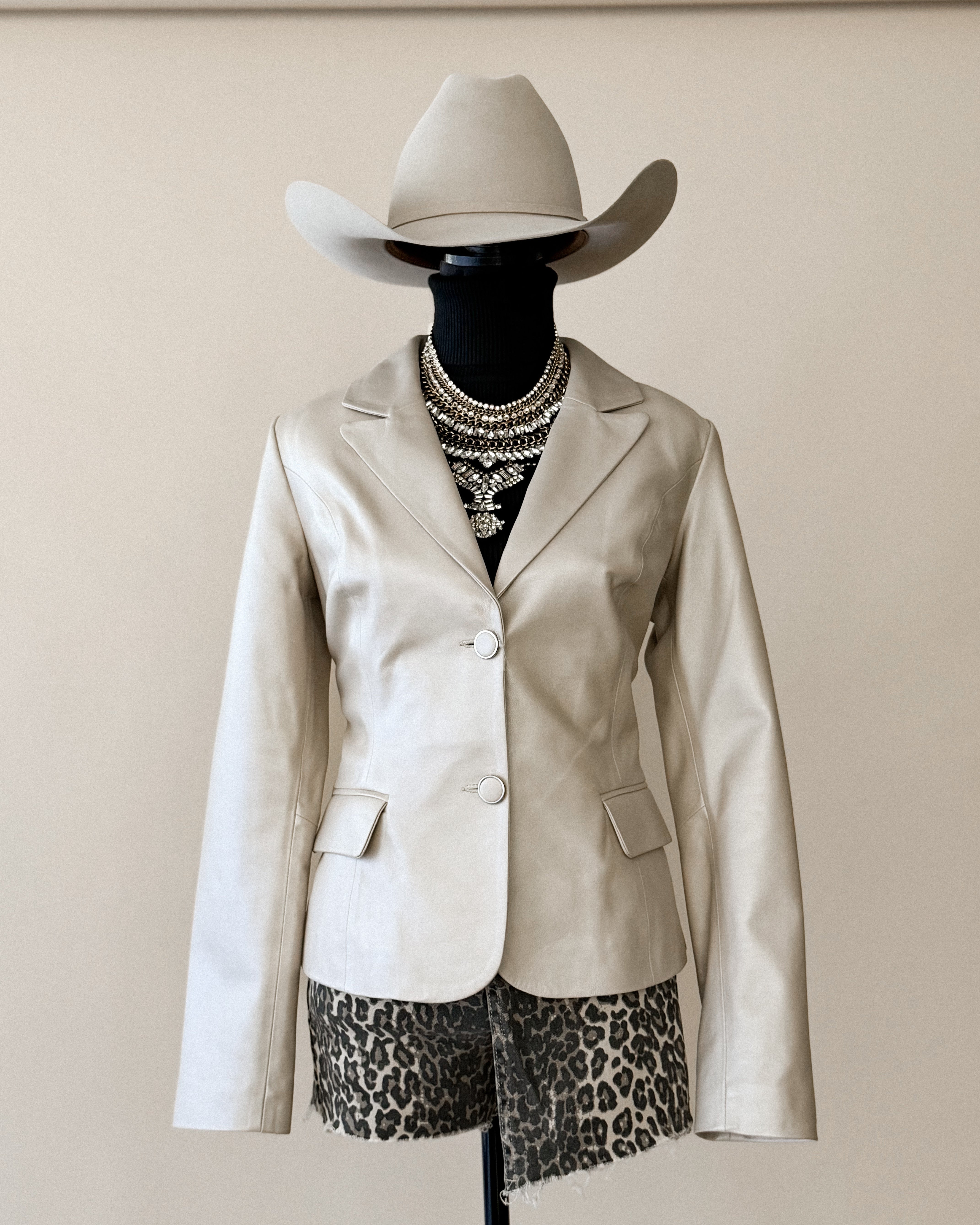 Western boho outfit with beige cowboy hat, cream blazer, leopard print shorts, layered necklaces