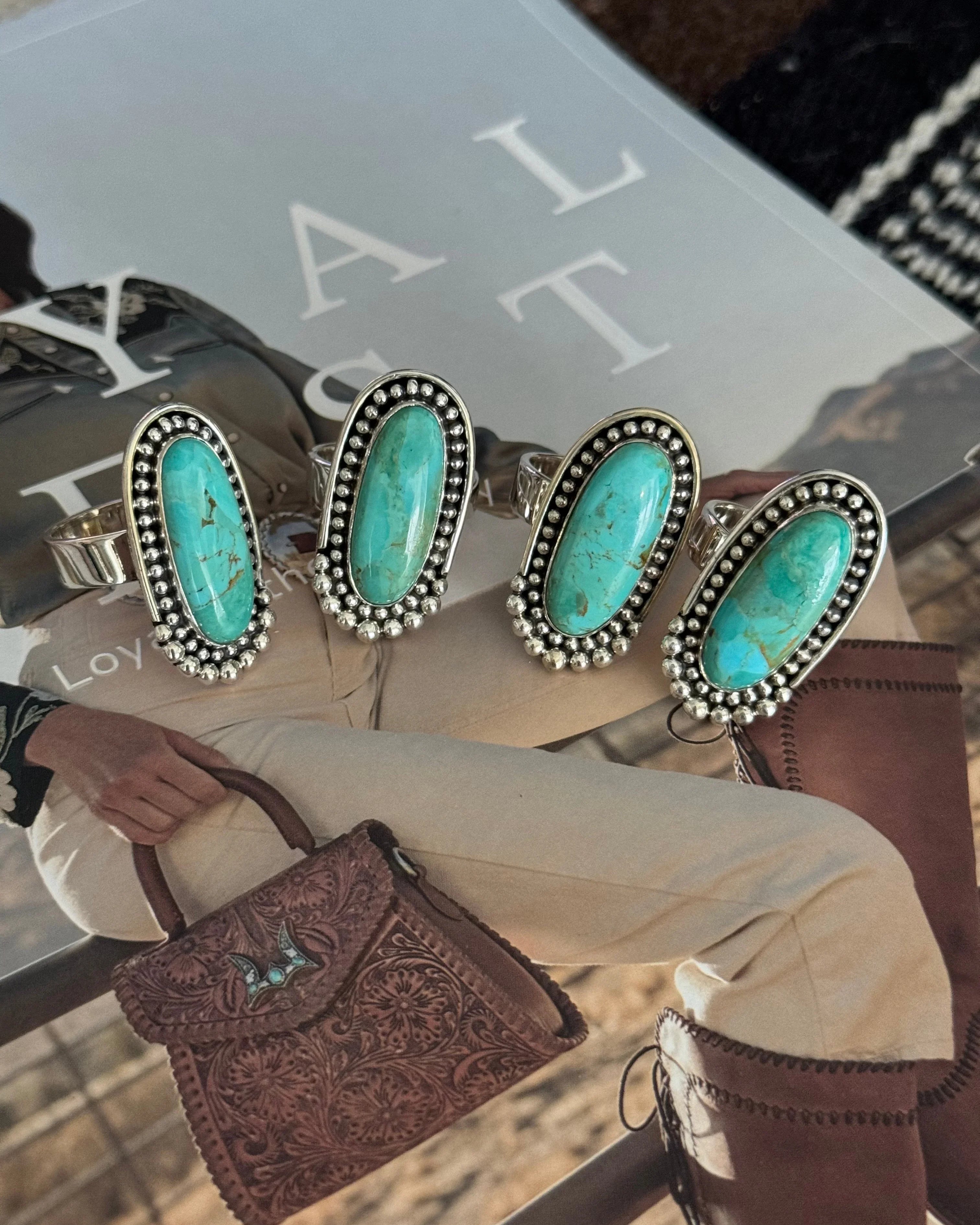Four silver rings with oval turquoise stones on western fashion magazine, cowgirl style accessories