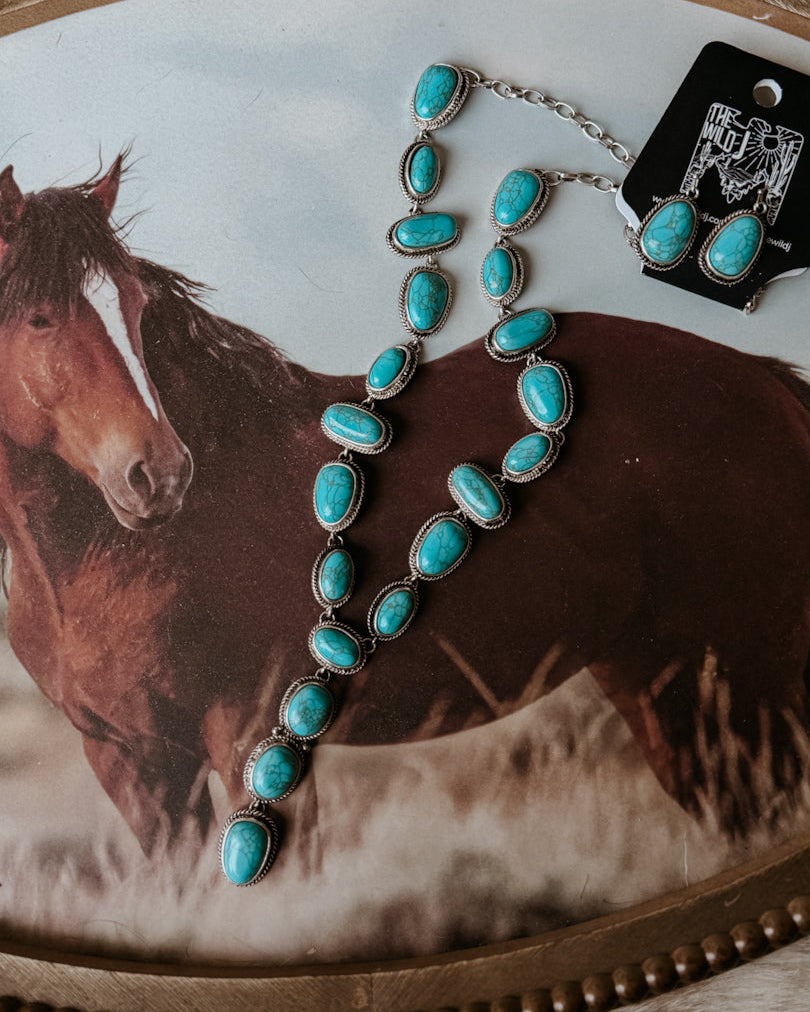 Thunderbird pendant chain necklace displayed on wooden slab with serape fabric underneath - The Wild J
