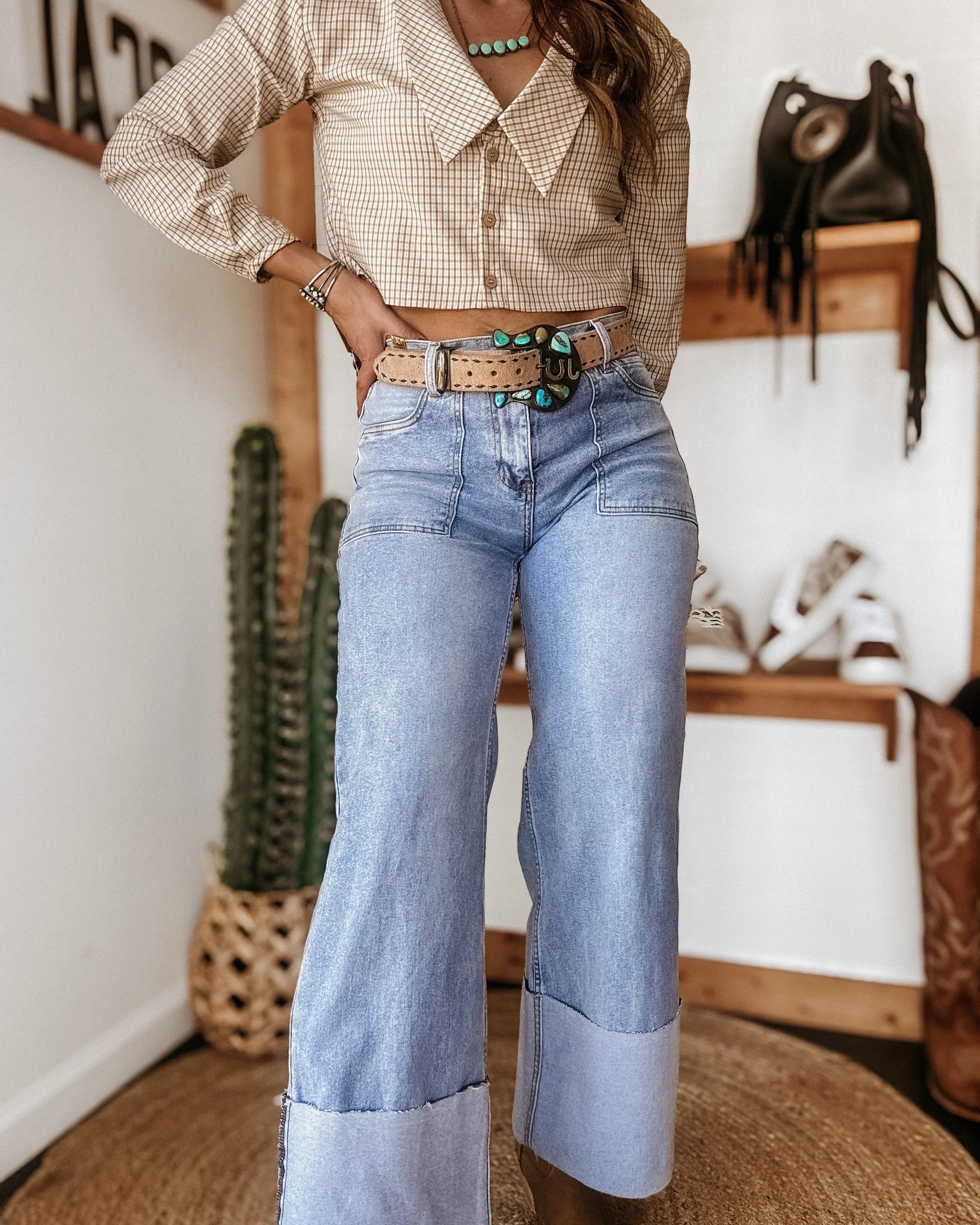 Woman in western boho outfit with cropped plaid top, turquoise belt, and wide-leg jeans