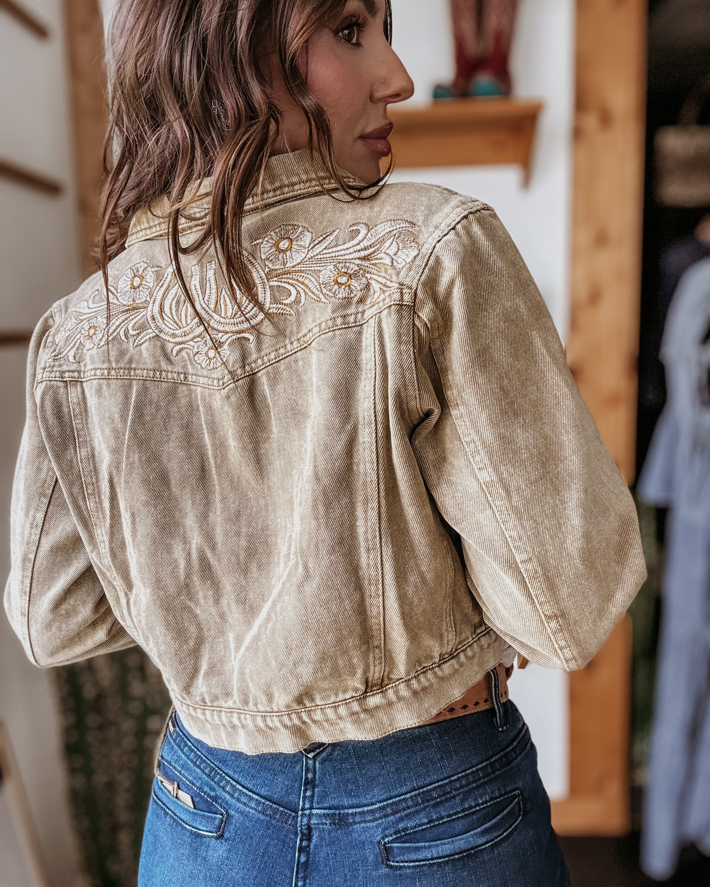 Woman wearing western cropped denim jacket with floral embroidery and high-waisted jeans