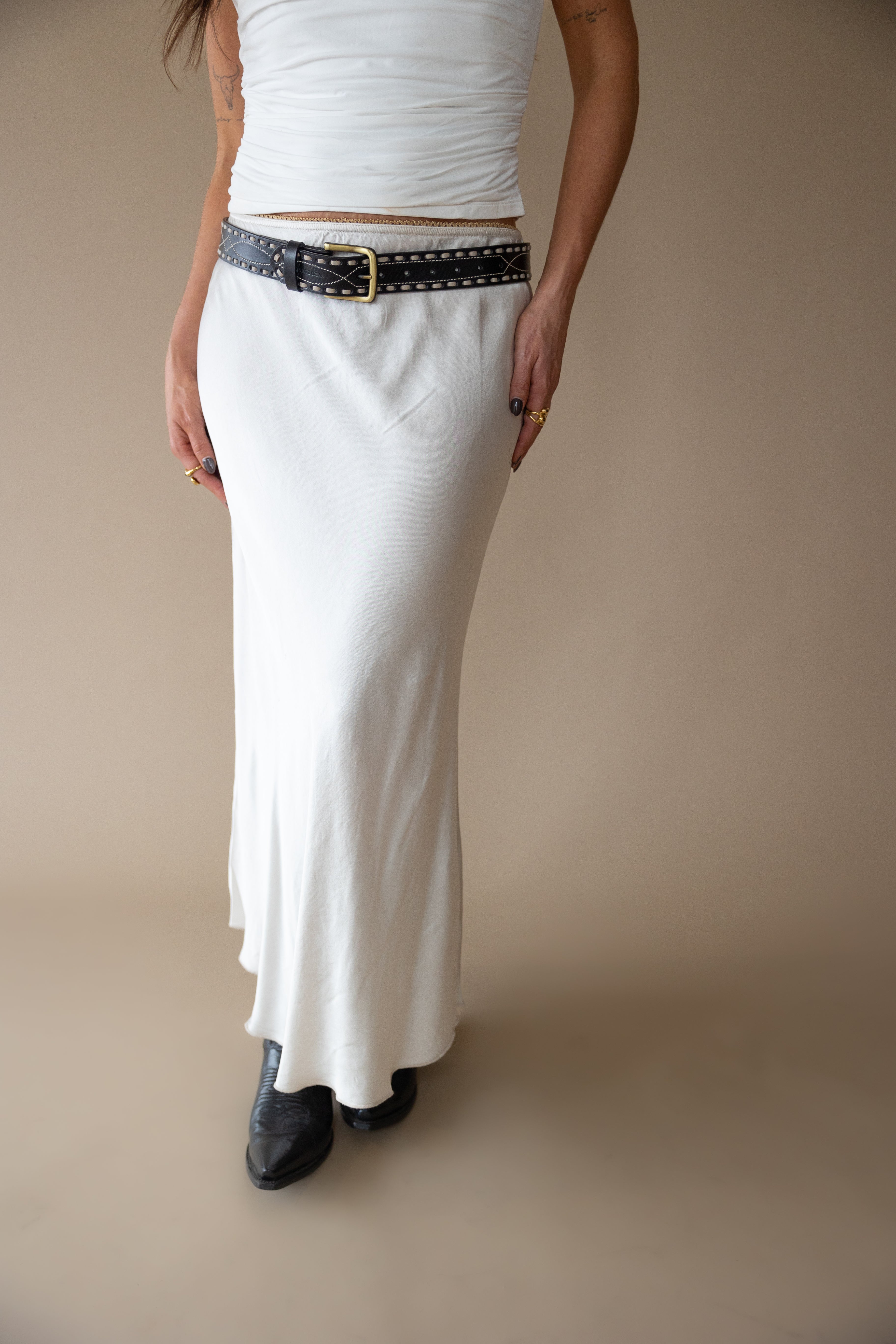 Woman in a white maxi skirt, studded black belt, western boots, western boho style