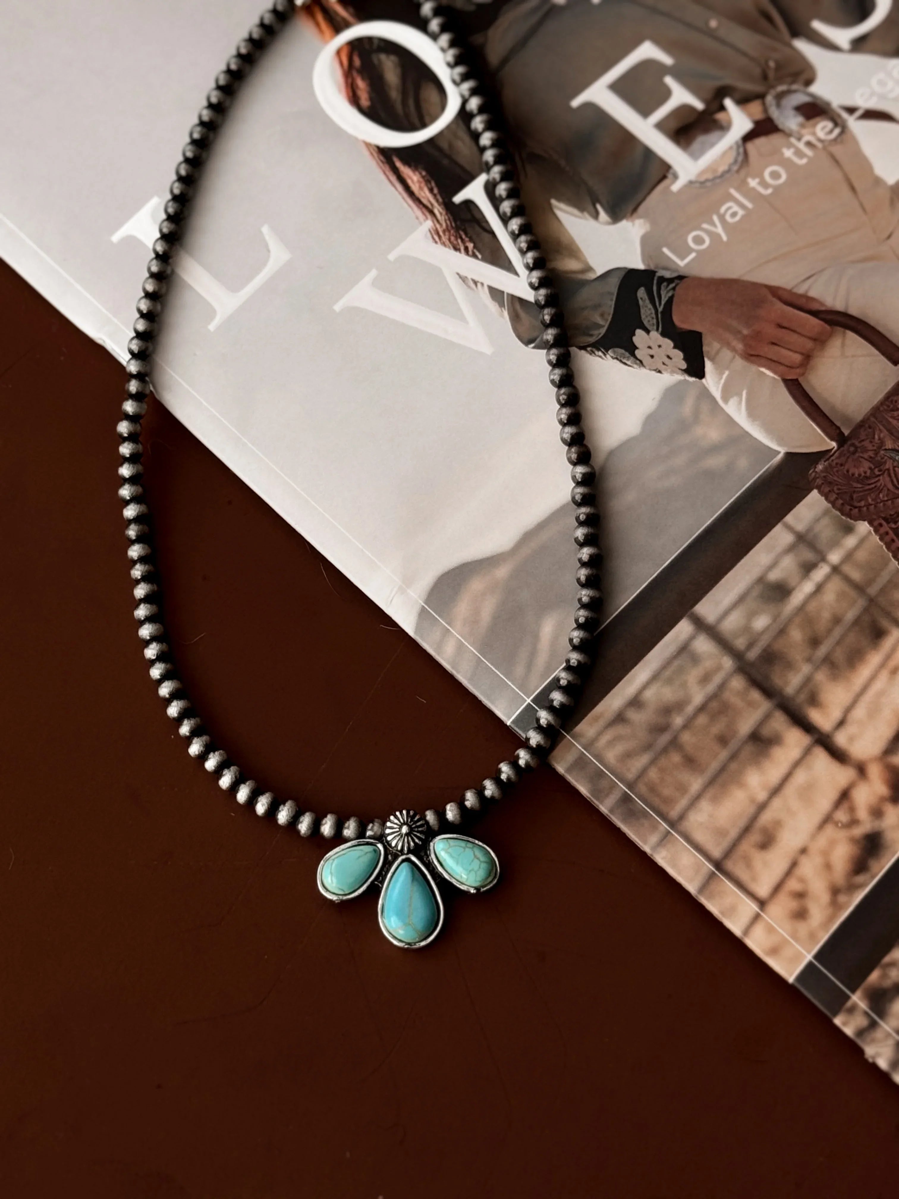 Necklace with turquoise pendant on a magazine