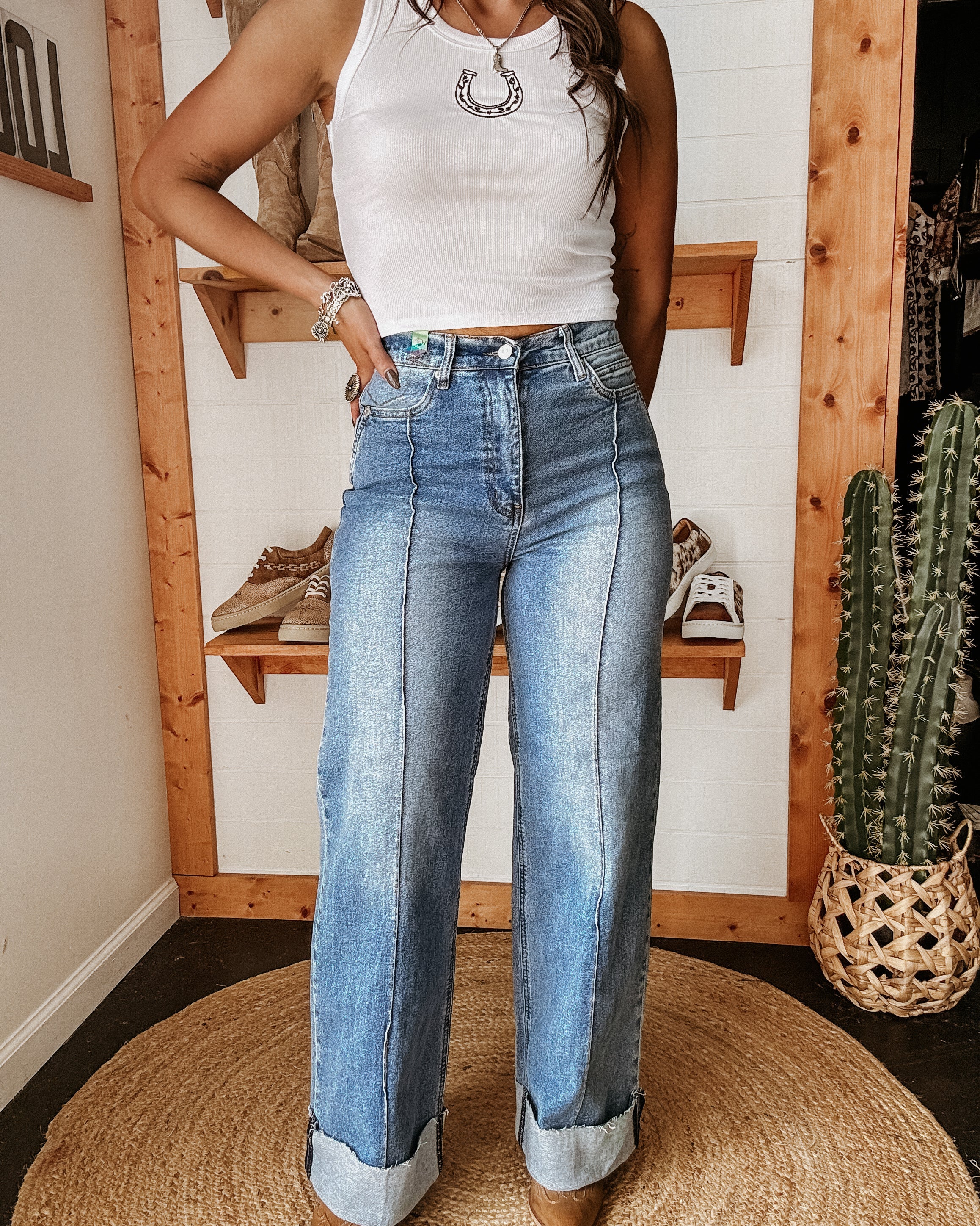 Woman wearing wide leg cuffed jeans, white tank top with horseshoe necklace, western boho style