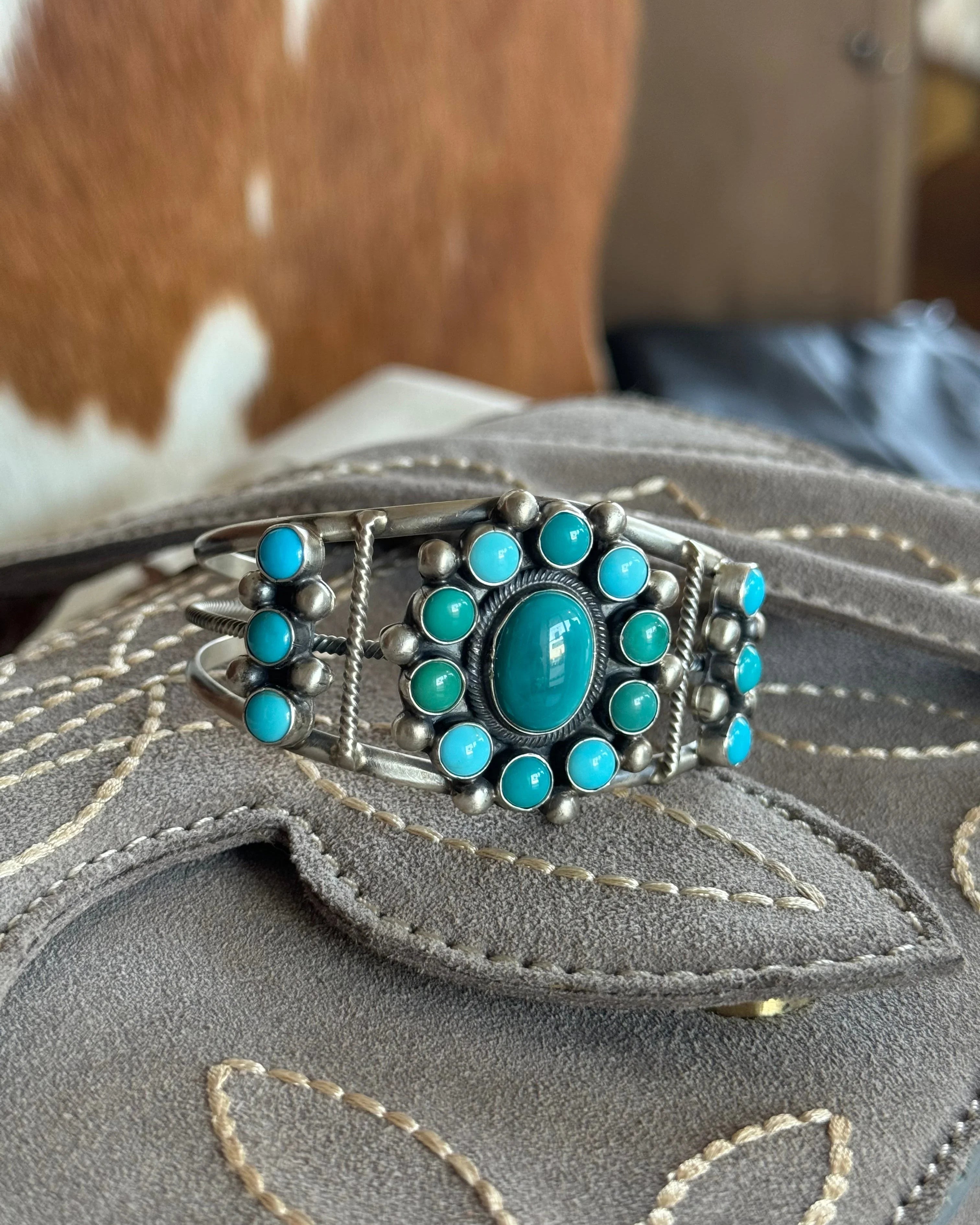 Western turquoise silver cuff bracelet with floral design on embroidered suede background