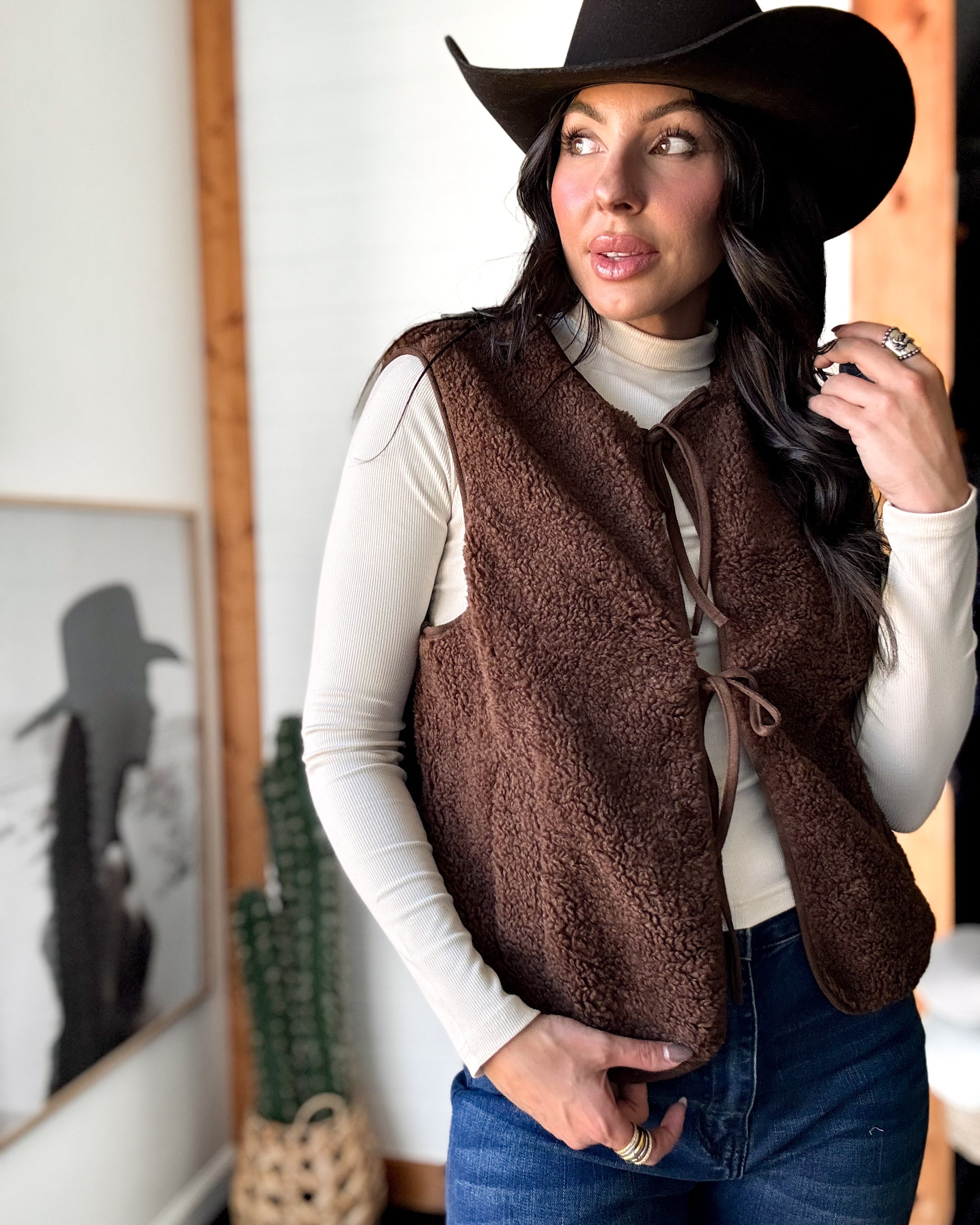 Woman wearing a brown vest and hat indoors