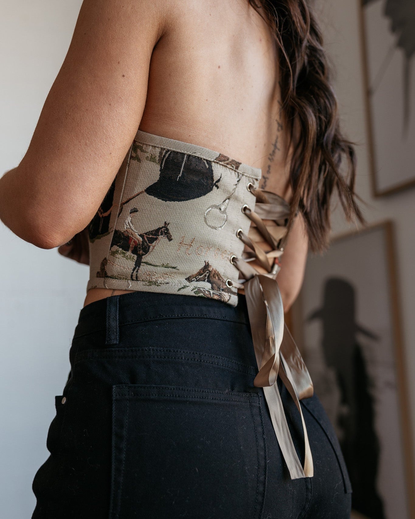 Woman wearing western print lace-up corset top and high-waisted black jeans