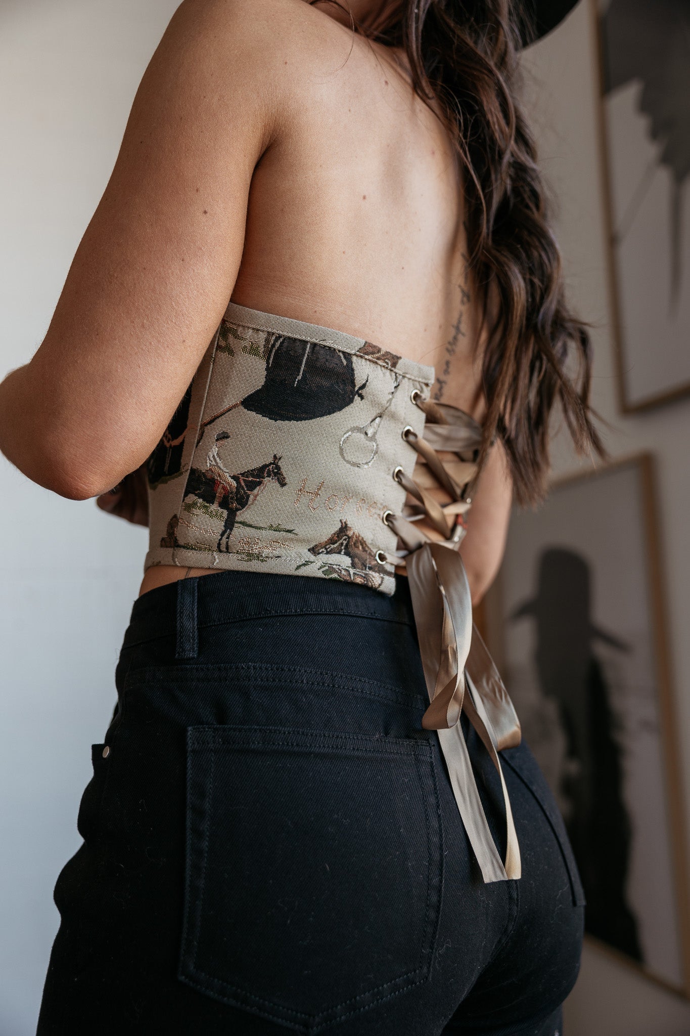 Woman wearing western print lace-up corset top and high-waisted black jeans