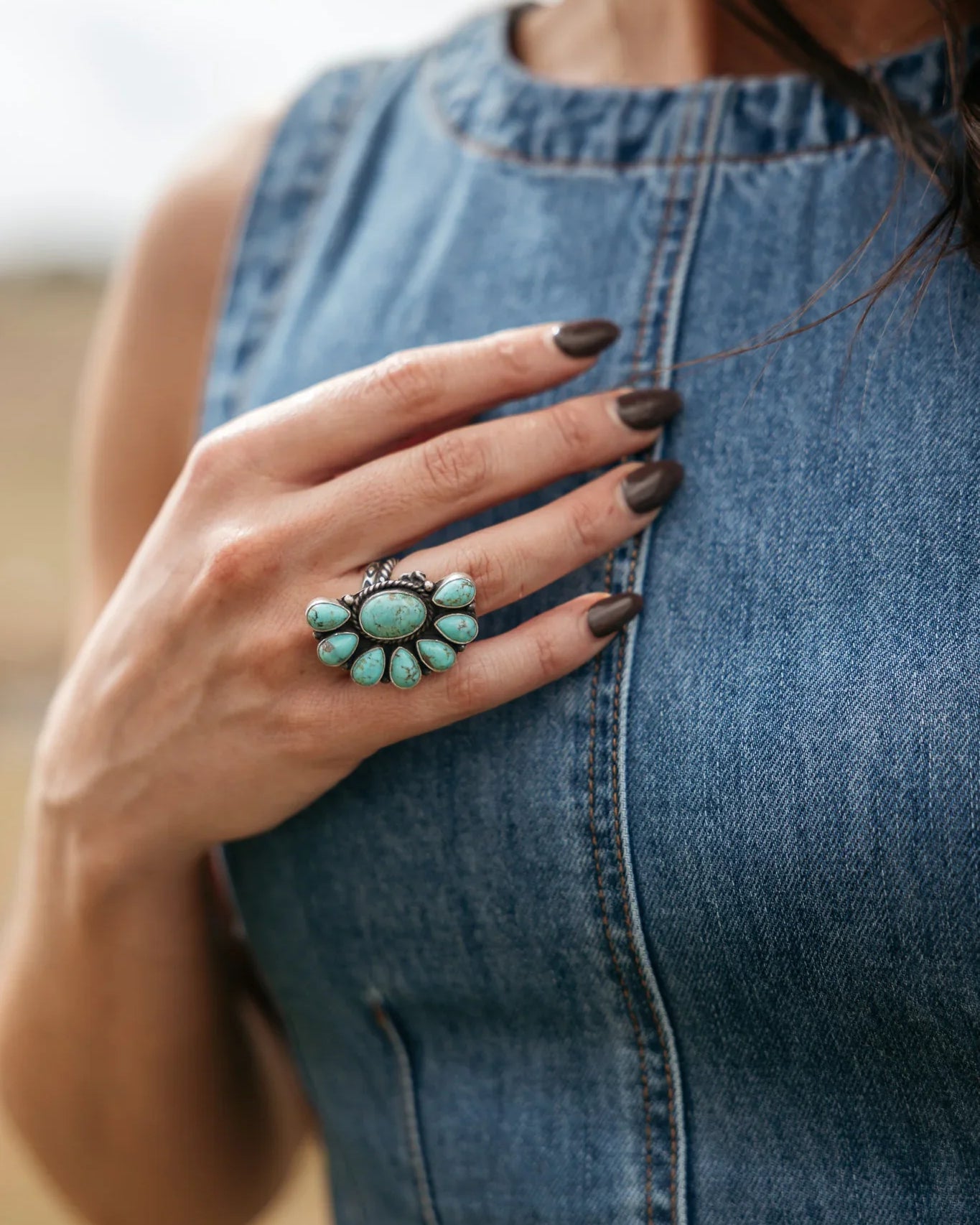 Woman wearing a turquoise western ring with denim sleeveless dress, boho cowgirl style