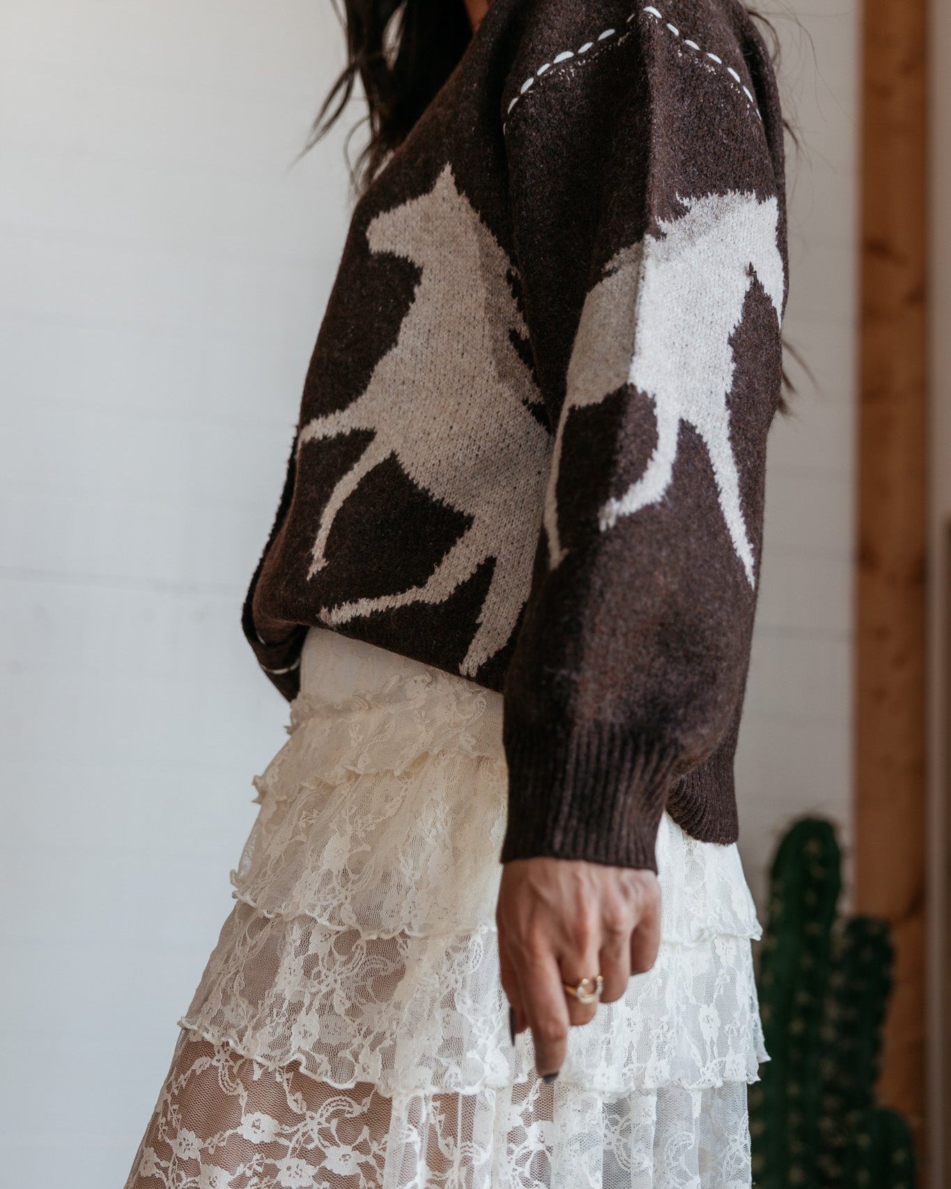 Woman in brown horse print sweater and tiered lace western skirt, boho cowgirl style