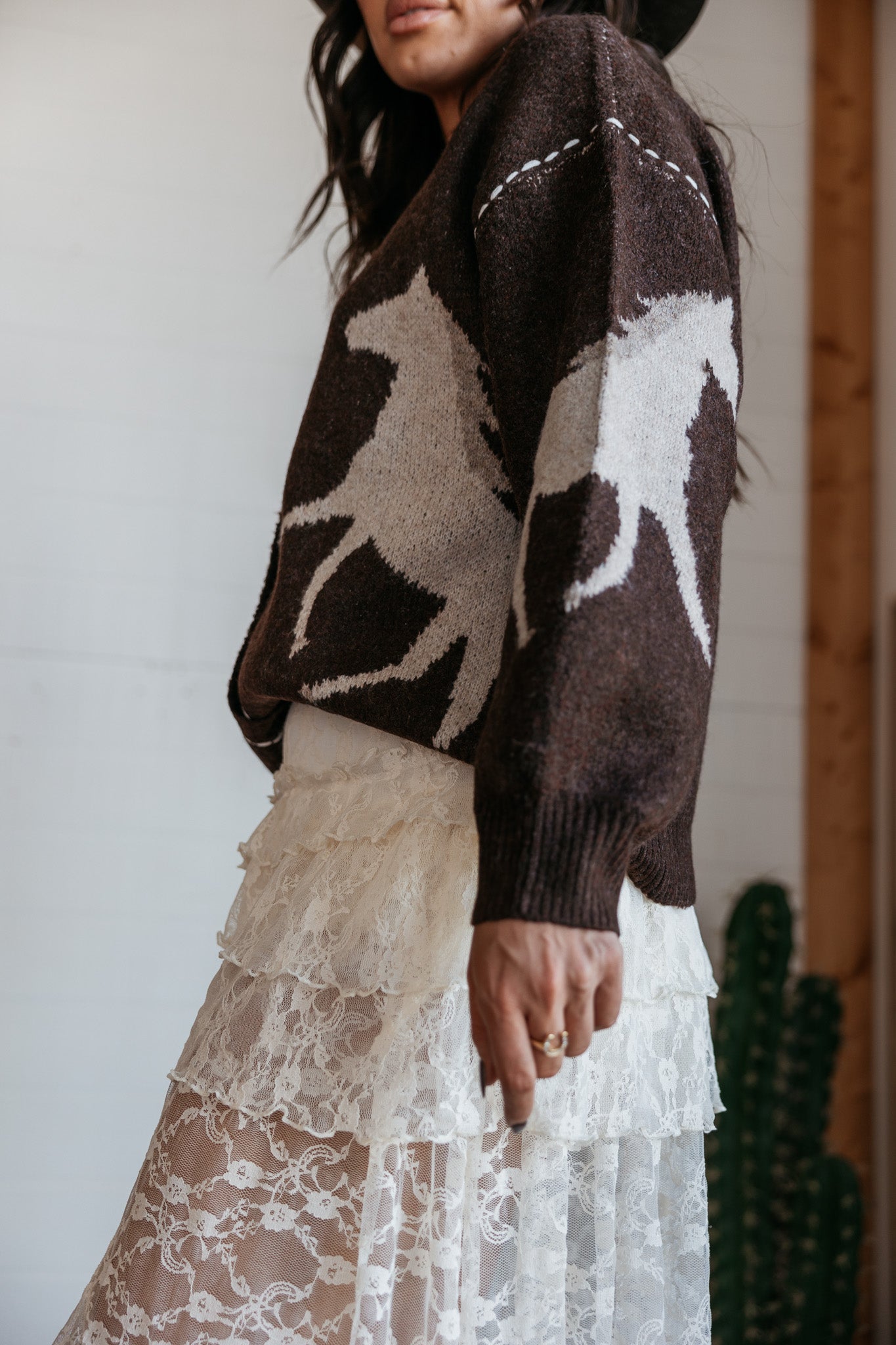 Woman in brown horse print sweater and tiered lace western skirt, boho cowgirl style