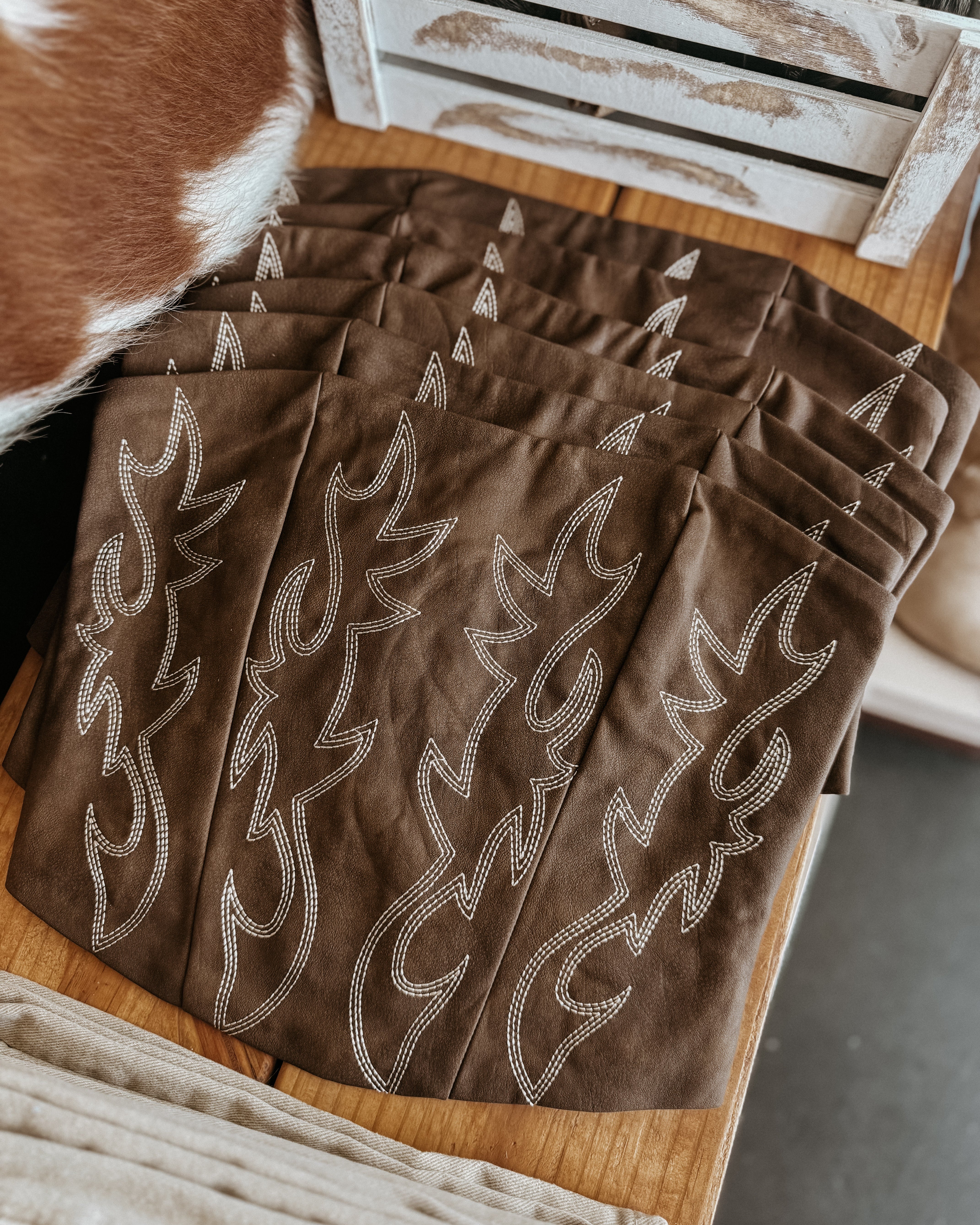 Brown western boho bandanas with white embroidered flame detailing on a wooden table