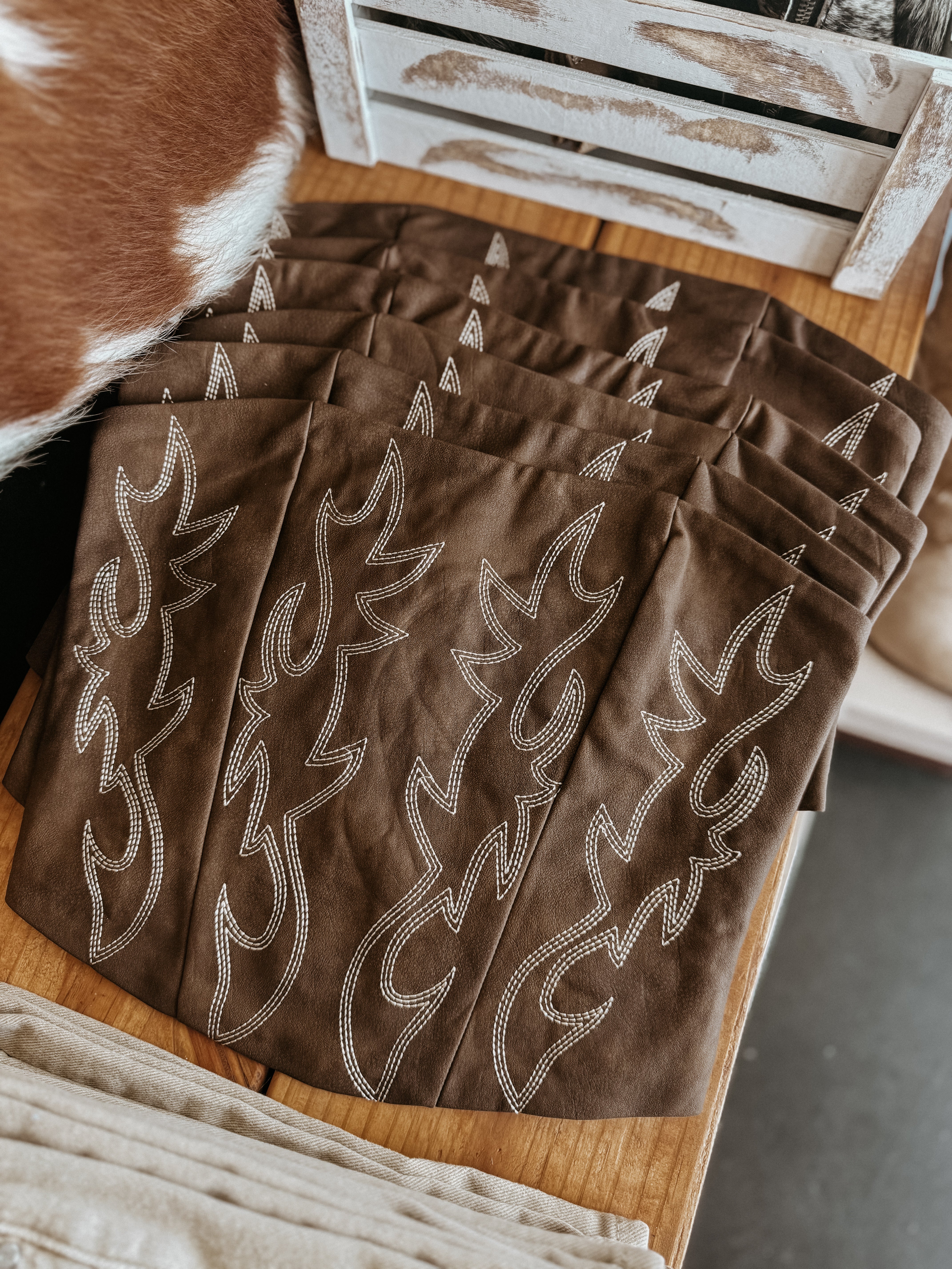 Brown western boho bandanas with white embroidered flame detailing on a wooden table
