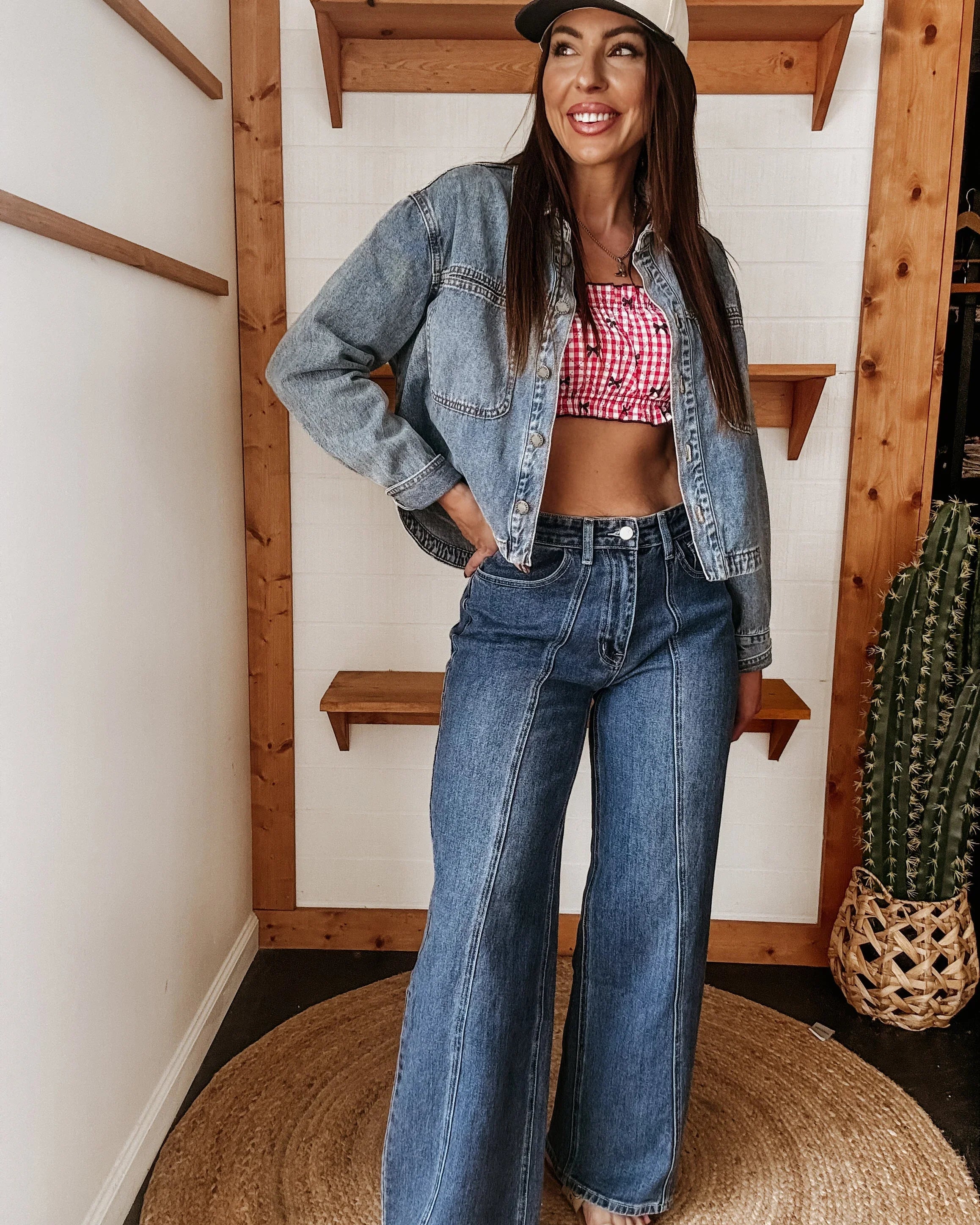 Woman in wide leg jeans, denim jacket, and cowgirl hat with western boho style indoors