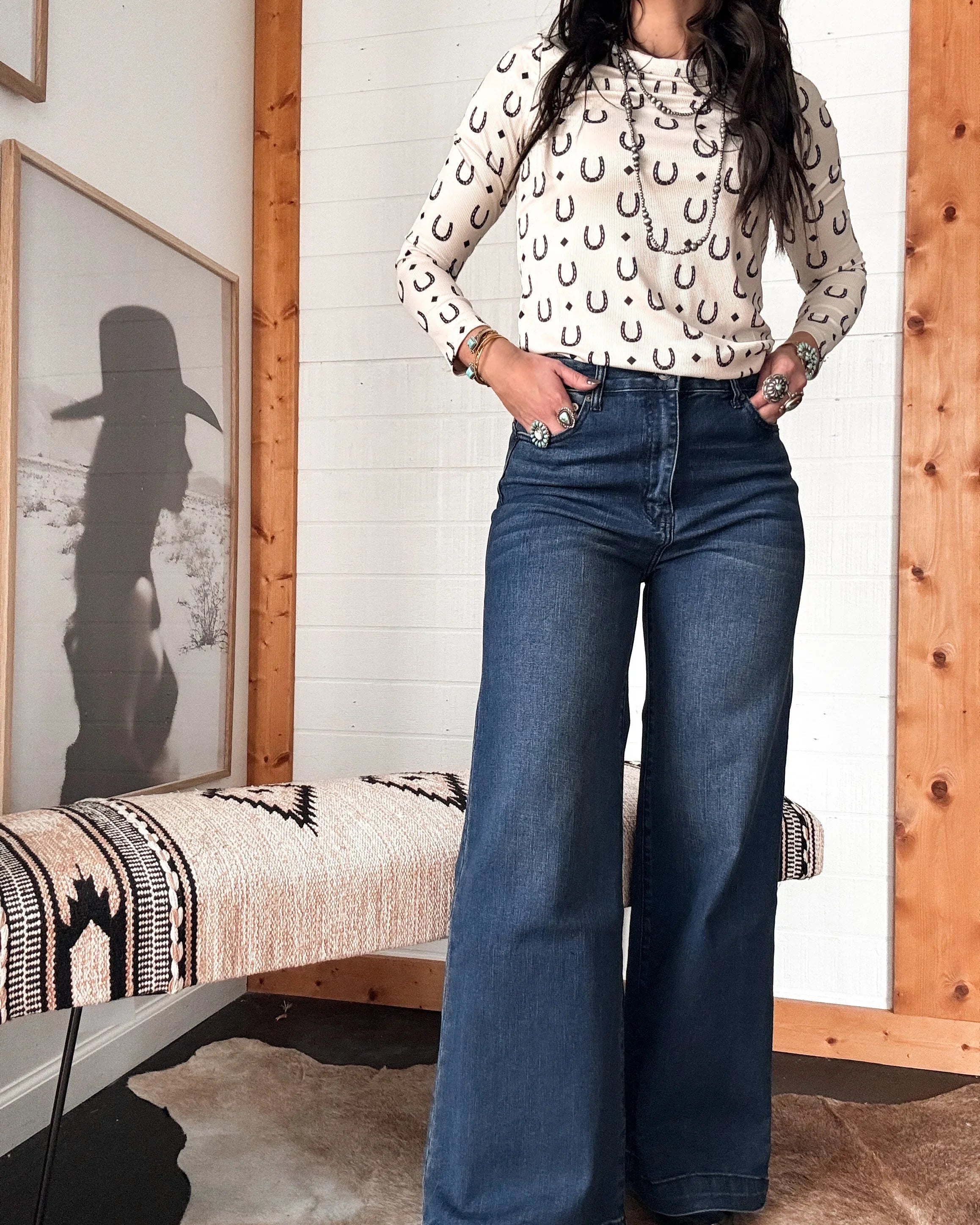 Woman in western boho outfit wearing horseshoe print long sleeve top and wide-leg jeans