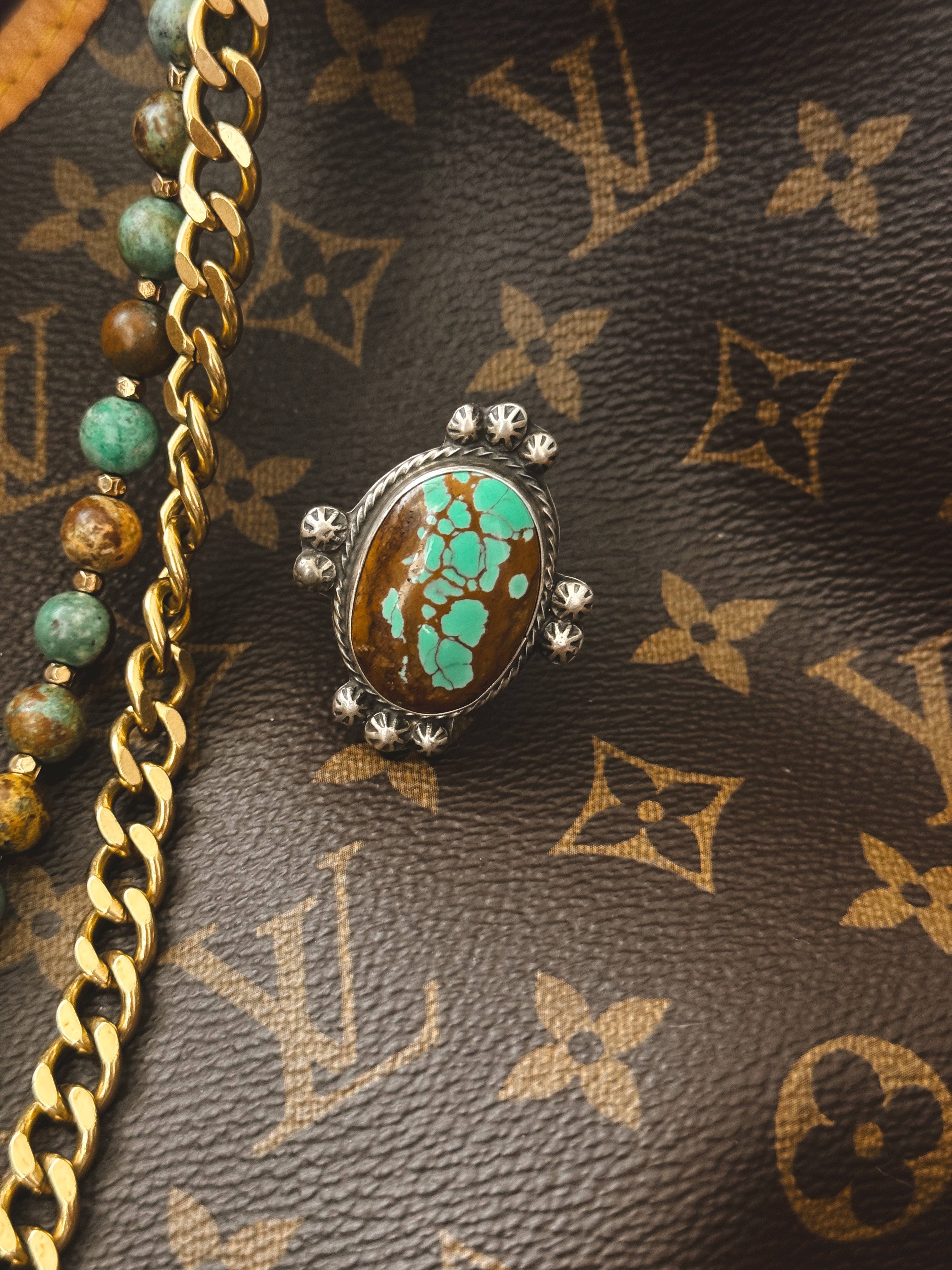 Thunderbird pendant chain necklace displayed on wooden slab with serape fabric underneath - The Wild J