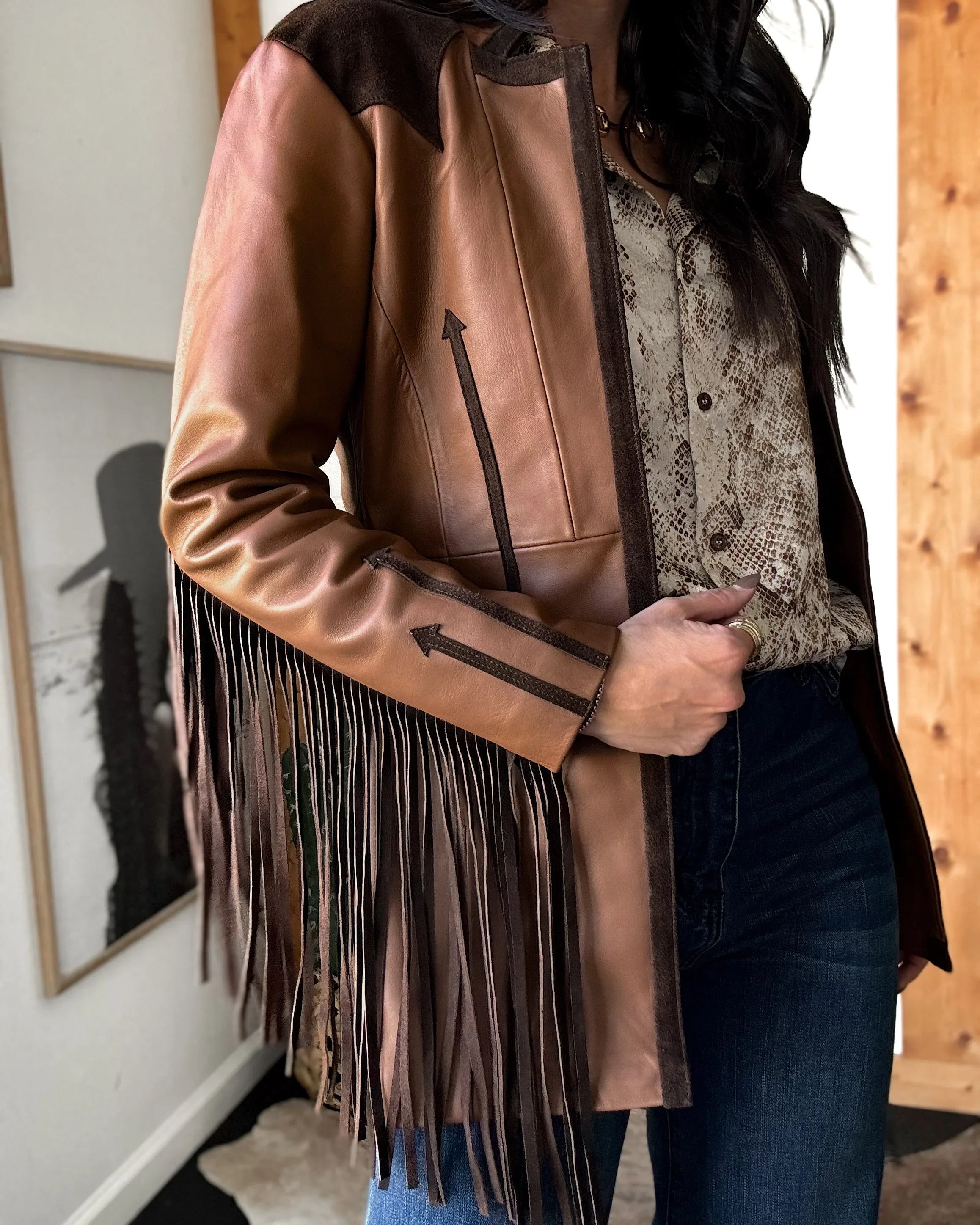 Woman wearing western fringe leather jacket, snakeskin blouse, blue jeans, cowgirl style