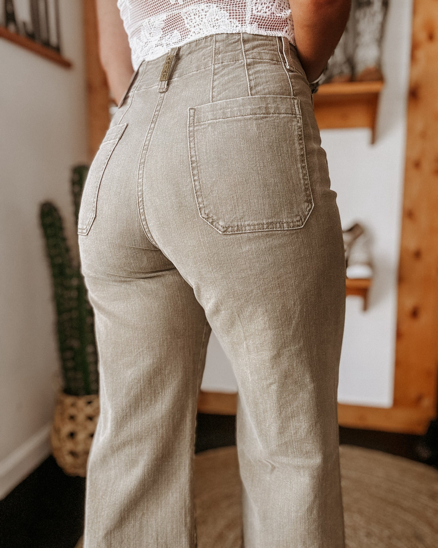 High-waisted western flare jeans styled with a lace top, boho boutique background