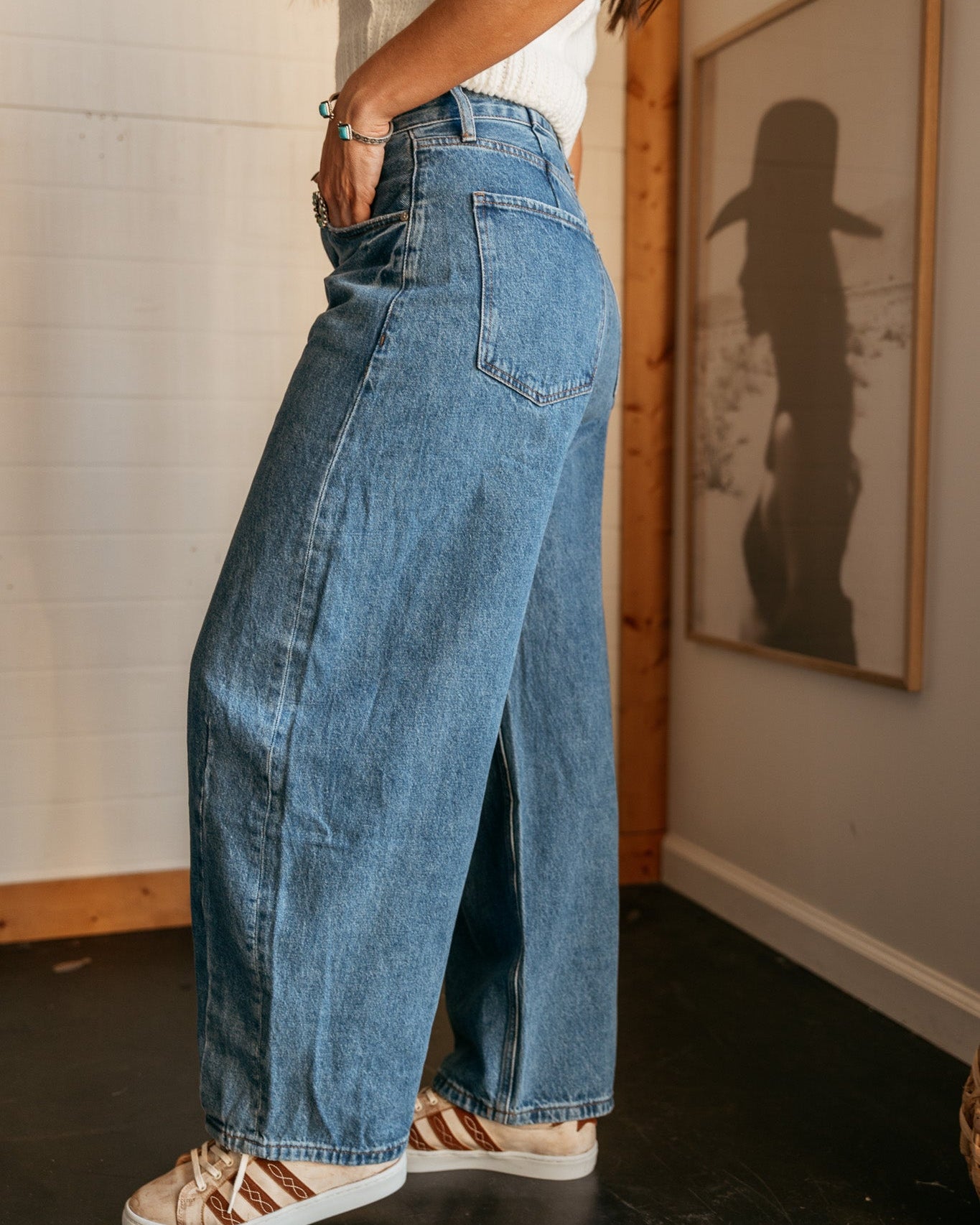 Woman in wide leg denim jeans and western sneakers, casual boho outfit indoors