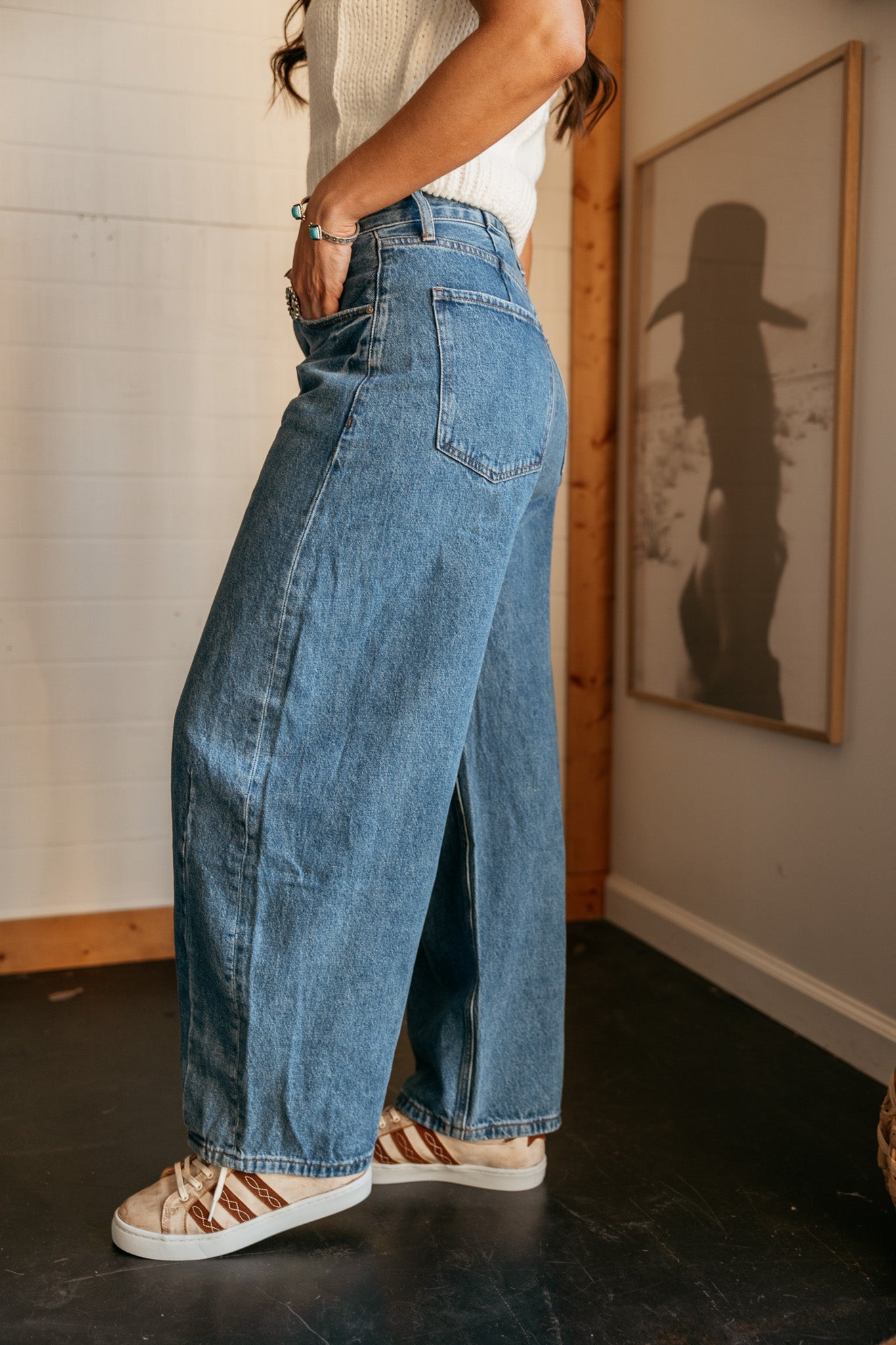 Woman in wide leg denim jeans and western sneakers, casual boho outfit indoors