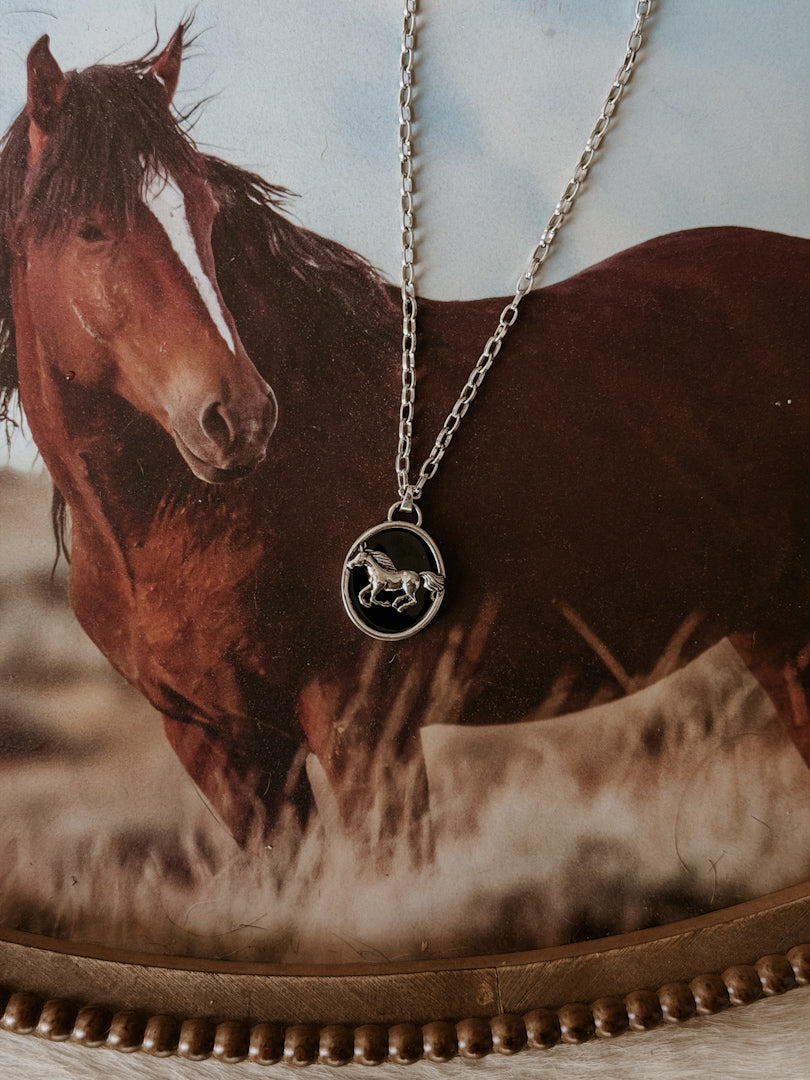 Thunderbird pendant chain necklace displayed on wooden slab with serape fabric underneath - The Wild J