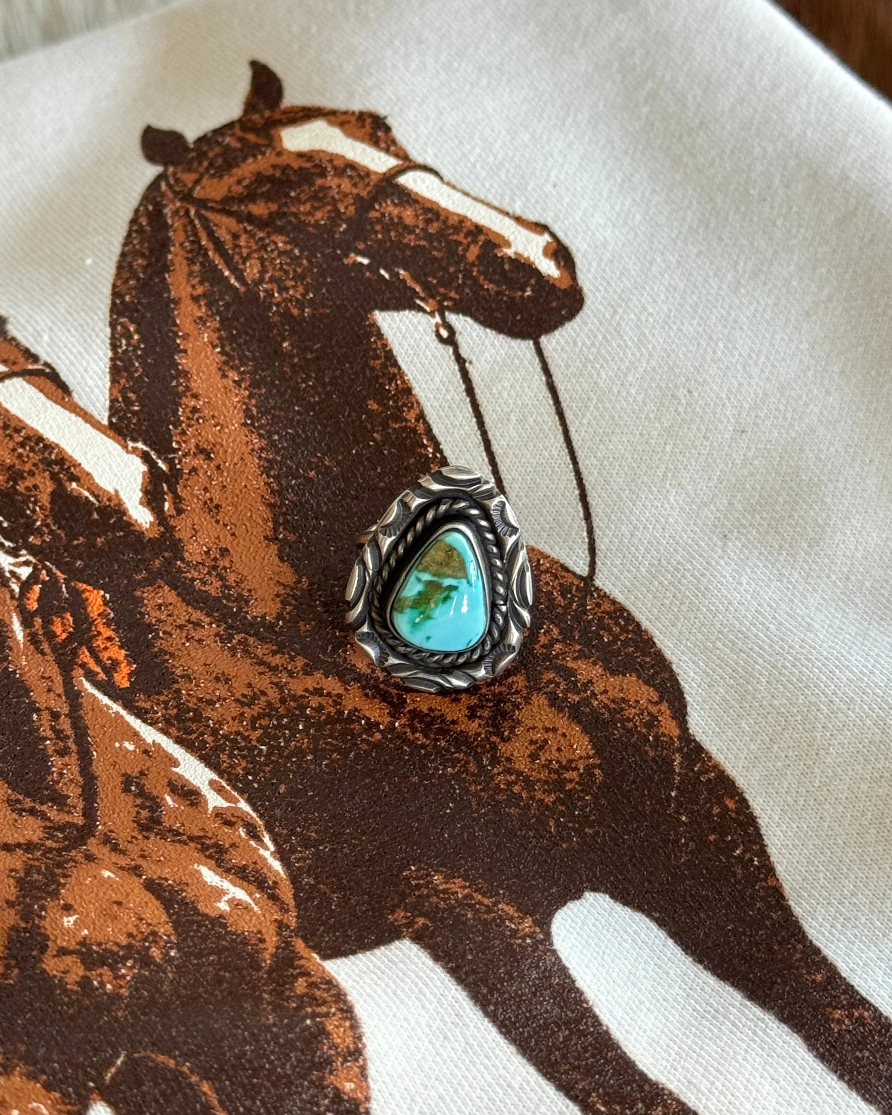 Turquoise western boho ring with silver detailing on a graphic horse print background