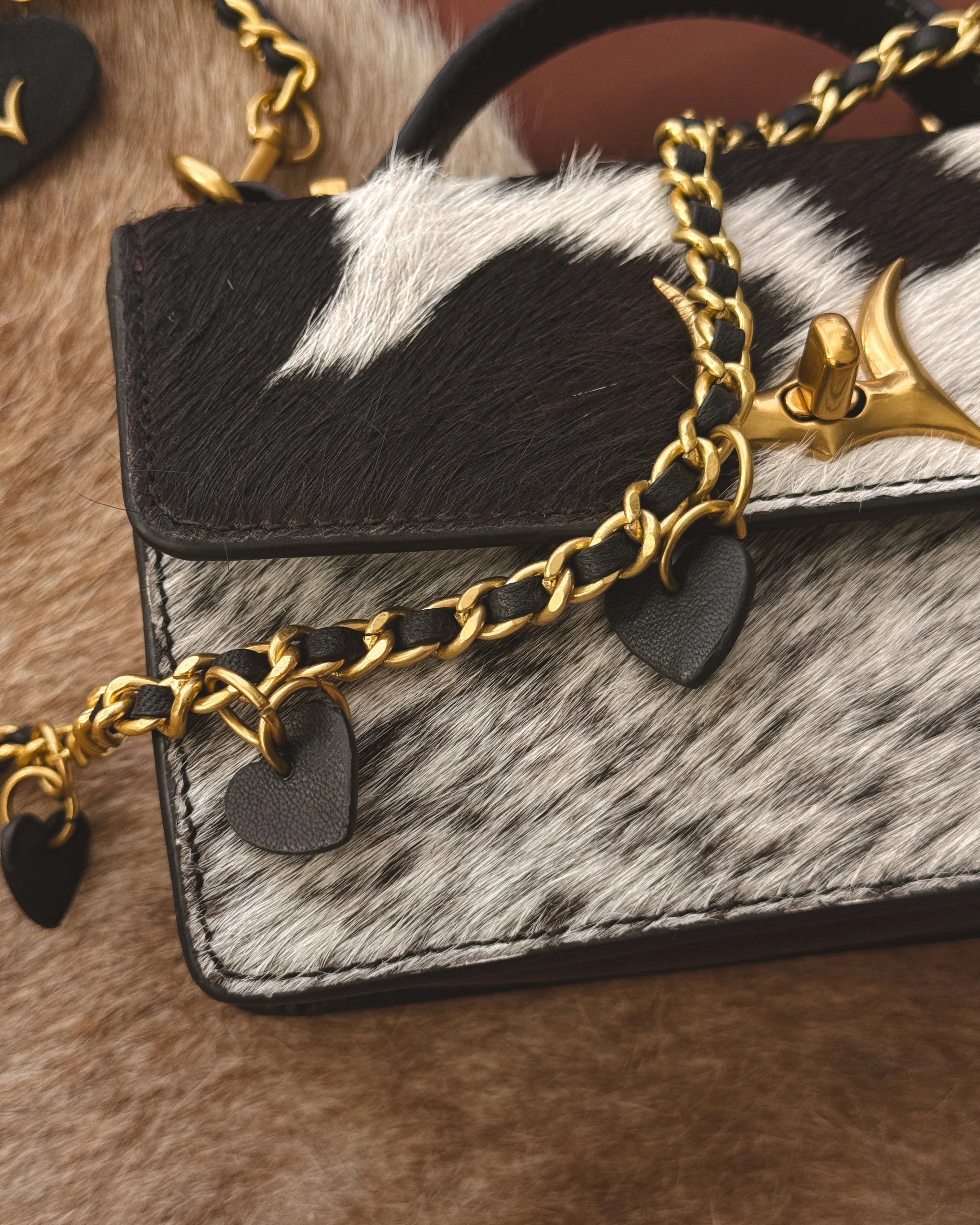 Handbag with gold chain and cowhide texture on a fur surface