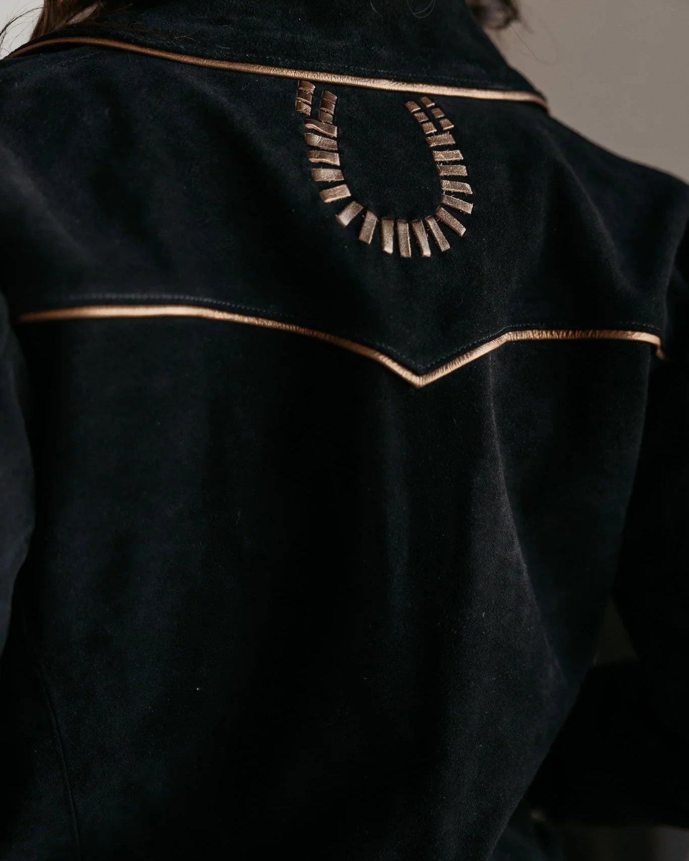Black western suede jacket with gold piping and metallic horseshoe detail on back