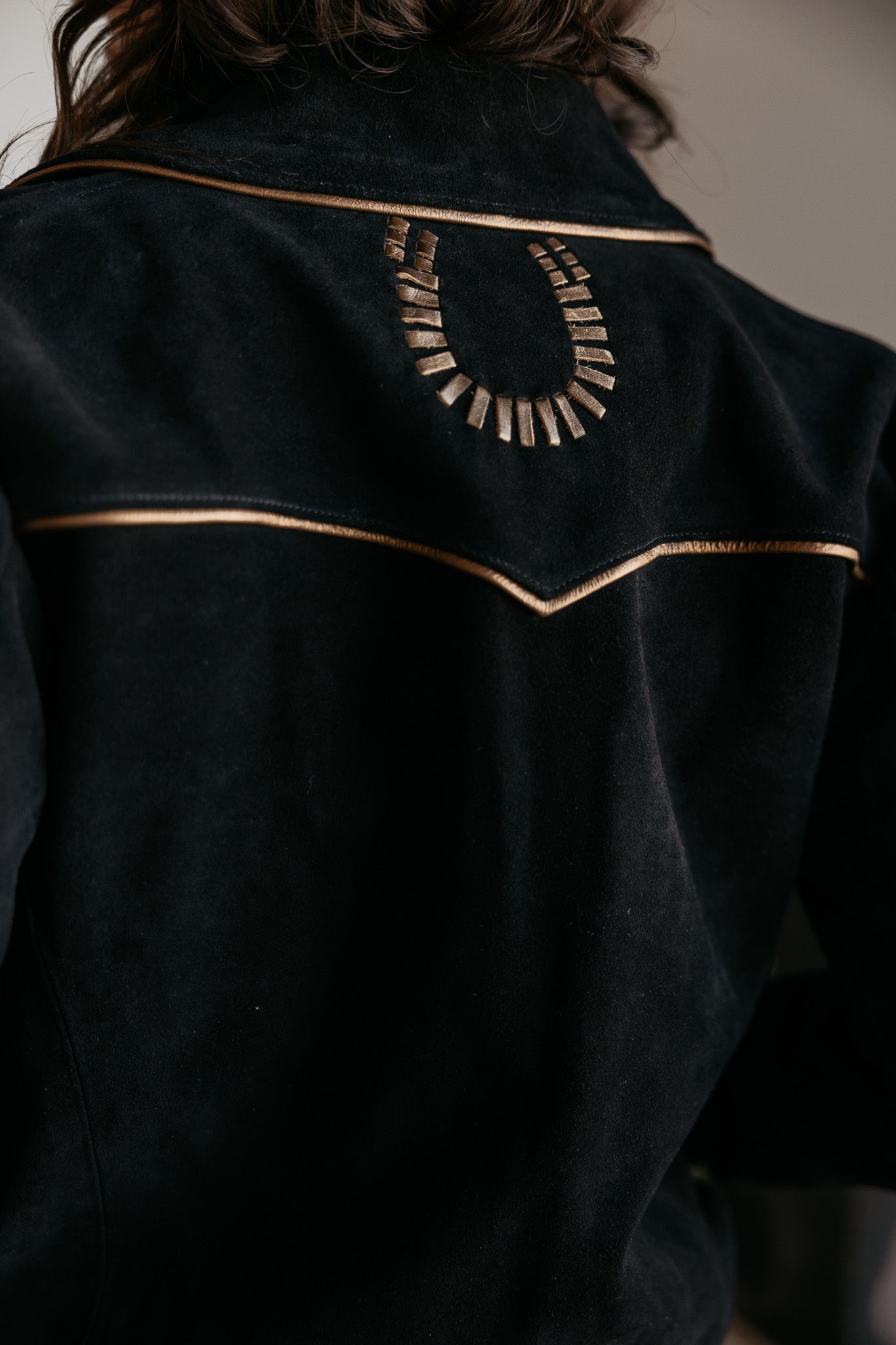 Black western suede jacket with gold piping and metallic horseshoe detail on back