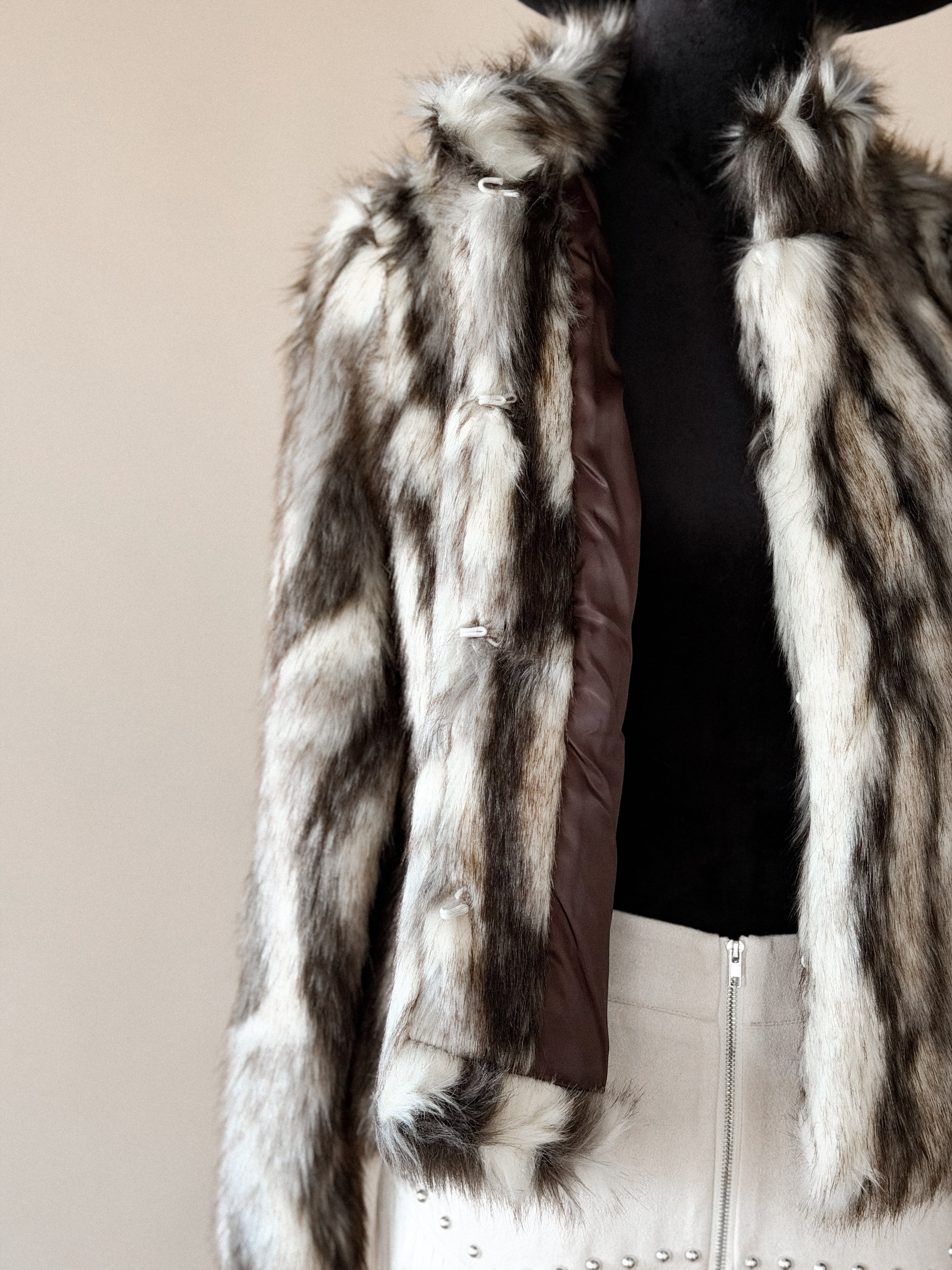 Western faux fur jacket with brown and white stripes, paired with a studded cream skirt.
