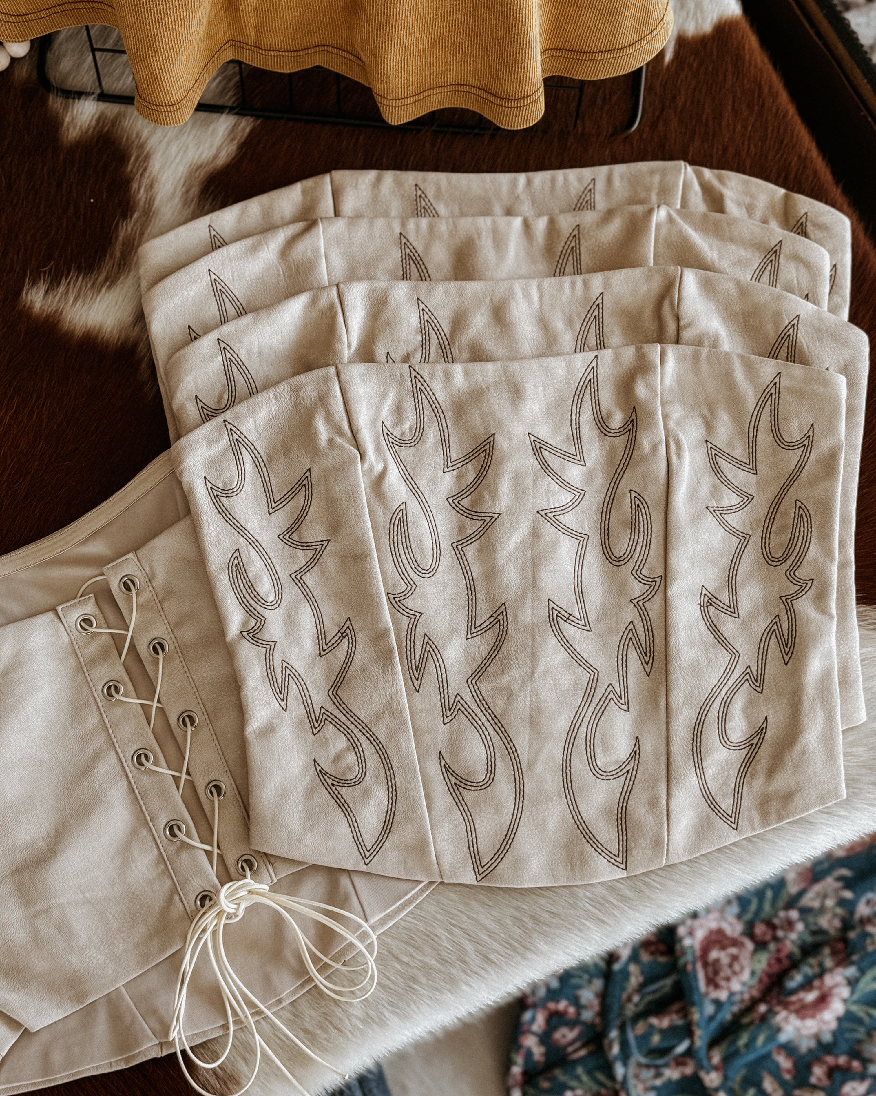 white corset top with embroidered designs on a wooden surface.